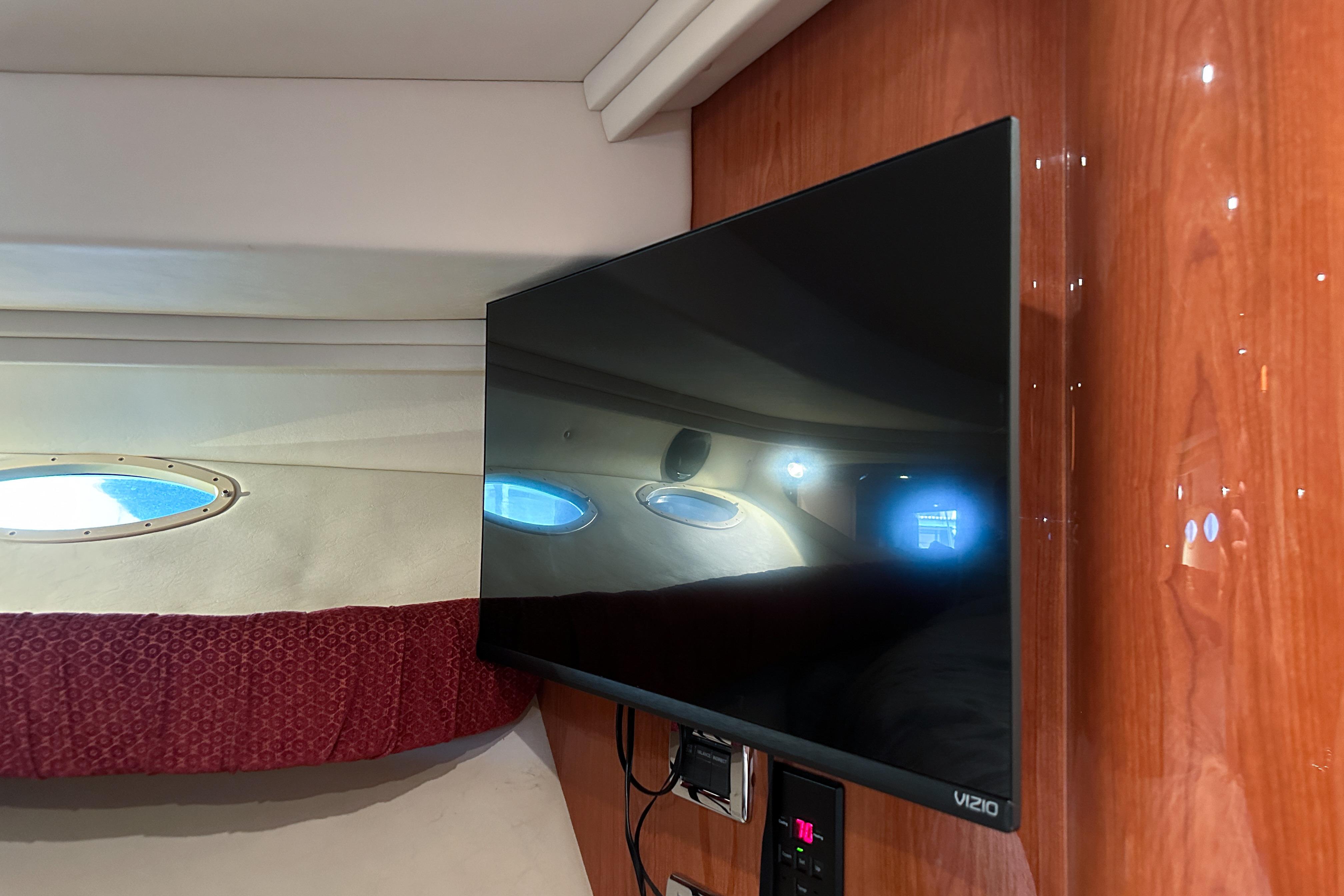 Flat-screen TV in 2001 Sea Ray 410 Sundancer cabin with porthole view.