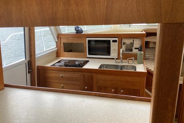 Interior of 2000 Mainship 430 Trawler featuring kitchen with stove, microwave, and sink.