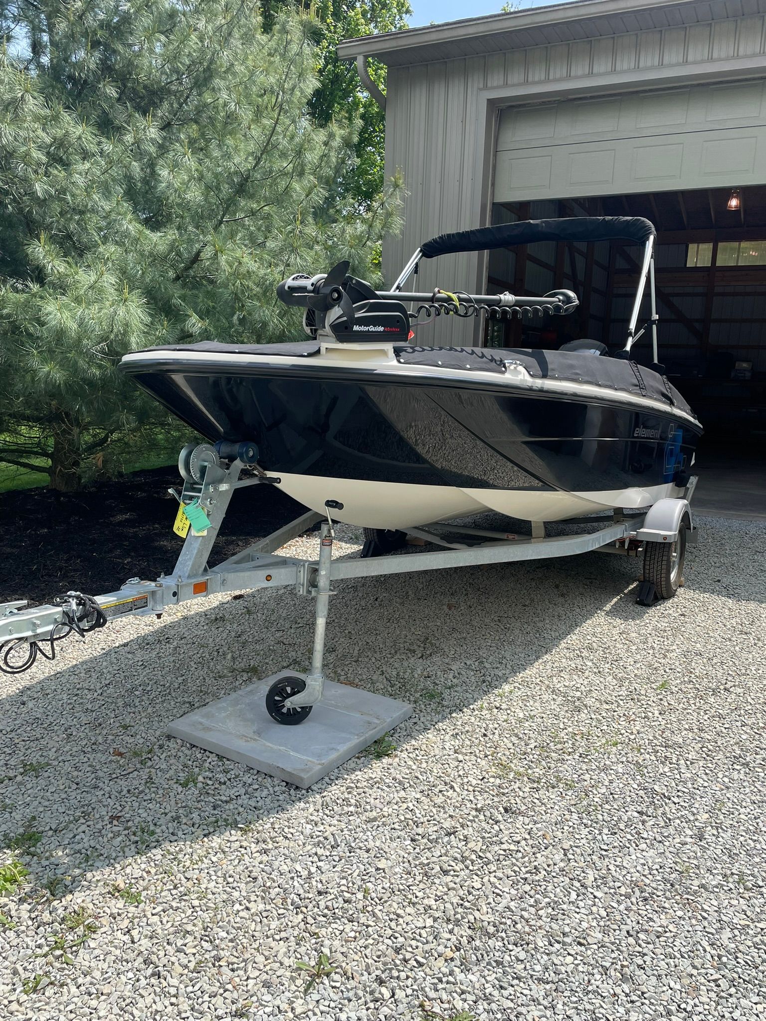 A 2018 Bayliner 160 Bowrider on a trailer in front of a garage.