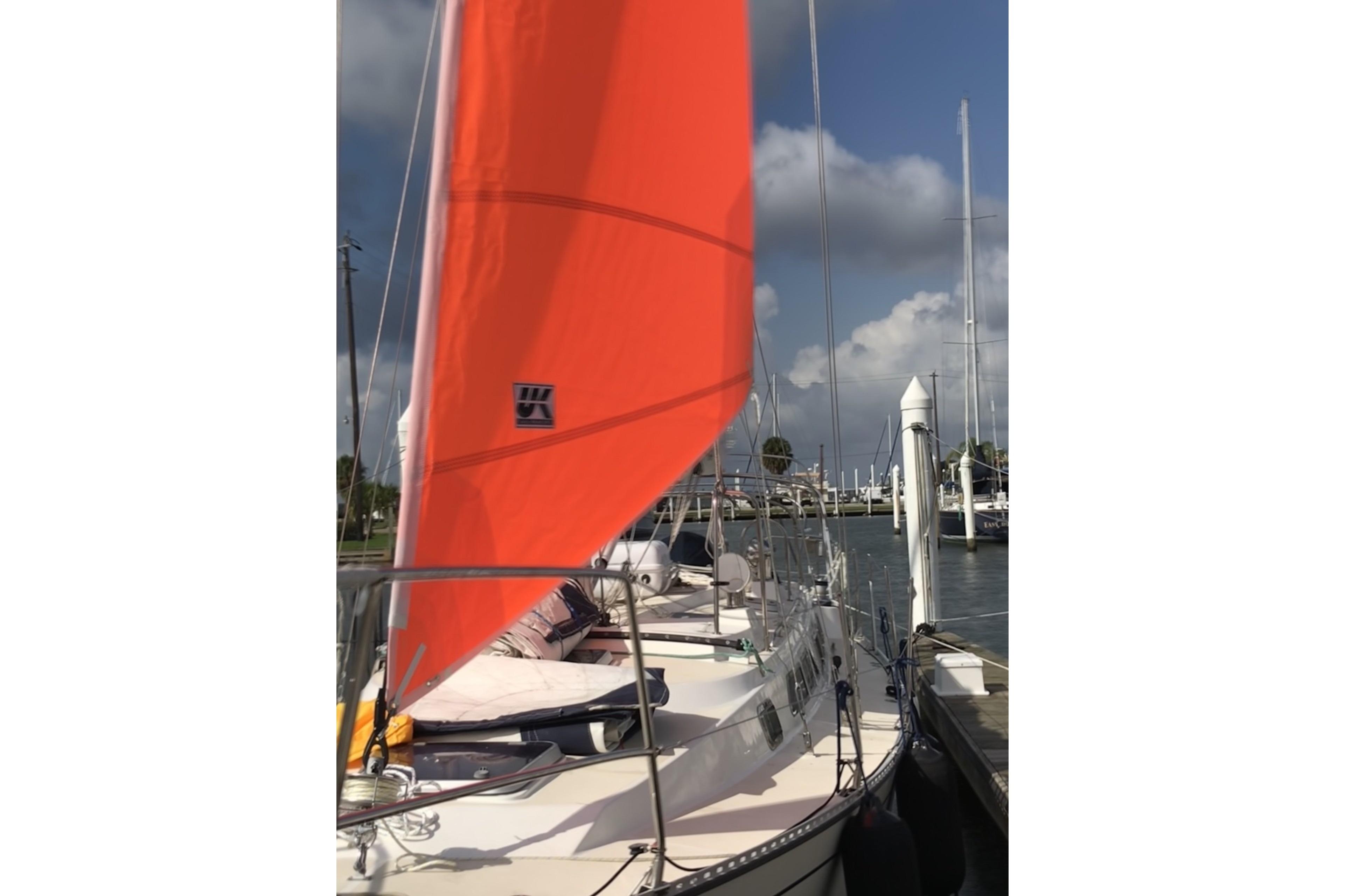 Sailboat Saga 43 (2002) with vibrant orange sail docked at marina.