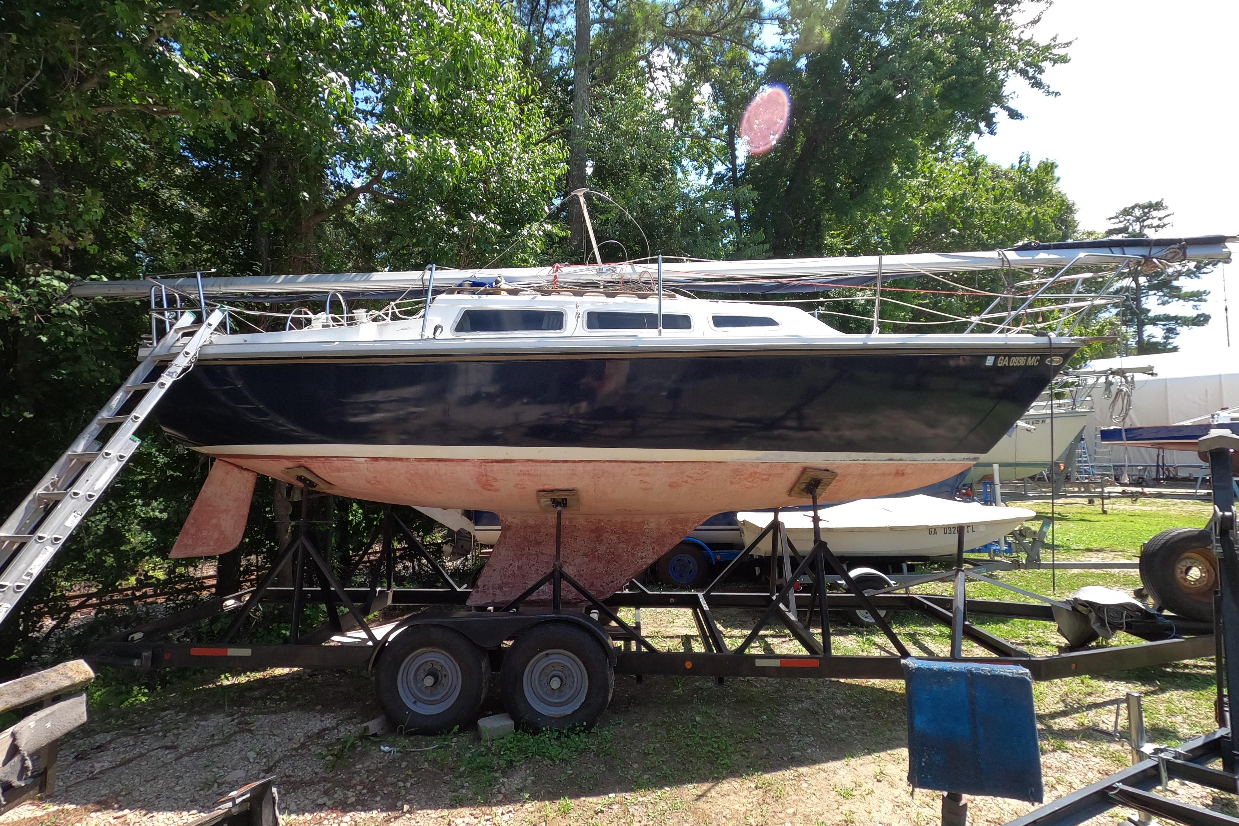 1984 Catalina 27 sailboat on trailer, surrounded by trees and equipment.