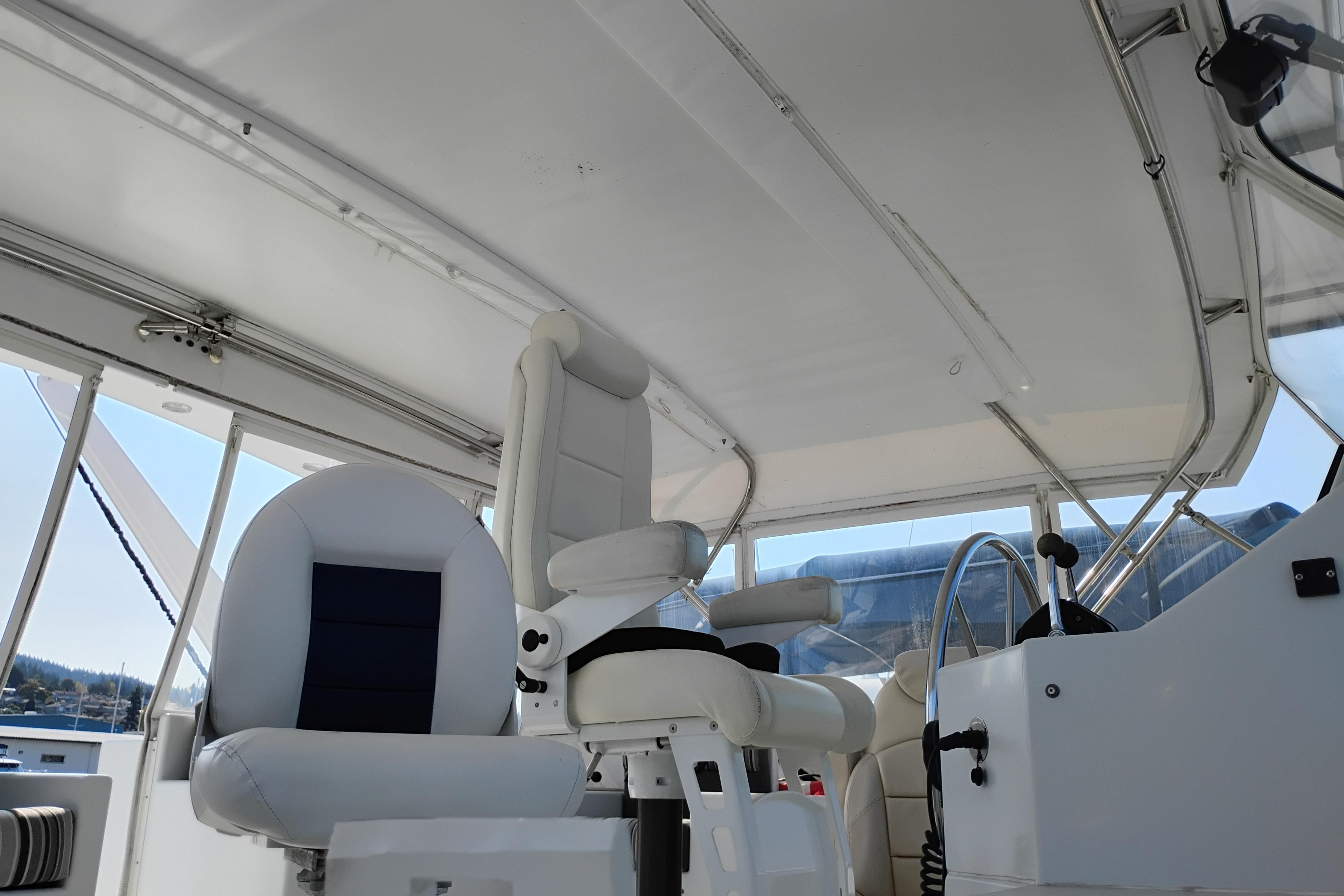 Interior view of 1995 Queenship 62 Pilothouse Motor Yacht helm with white seating.