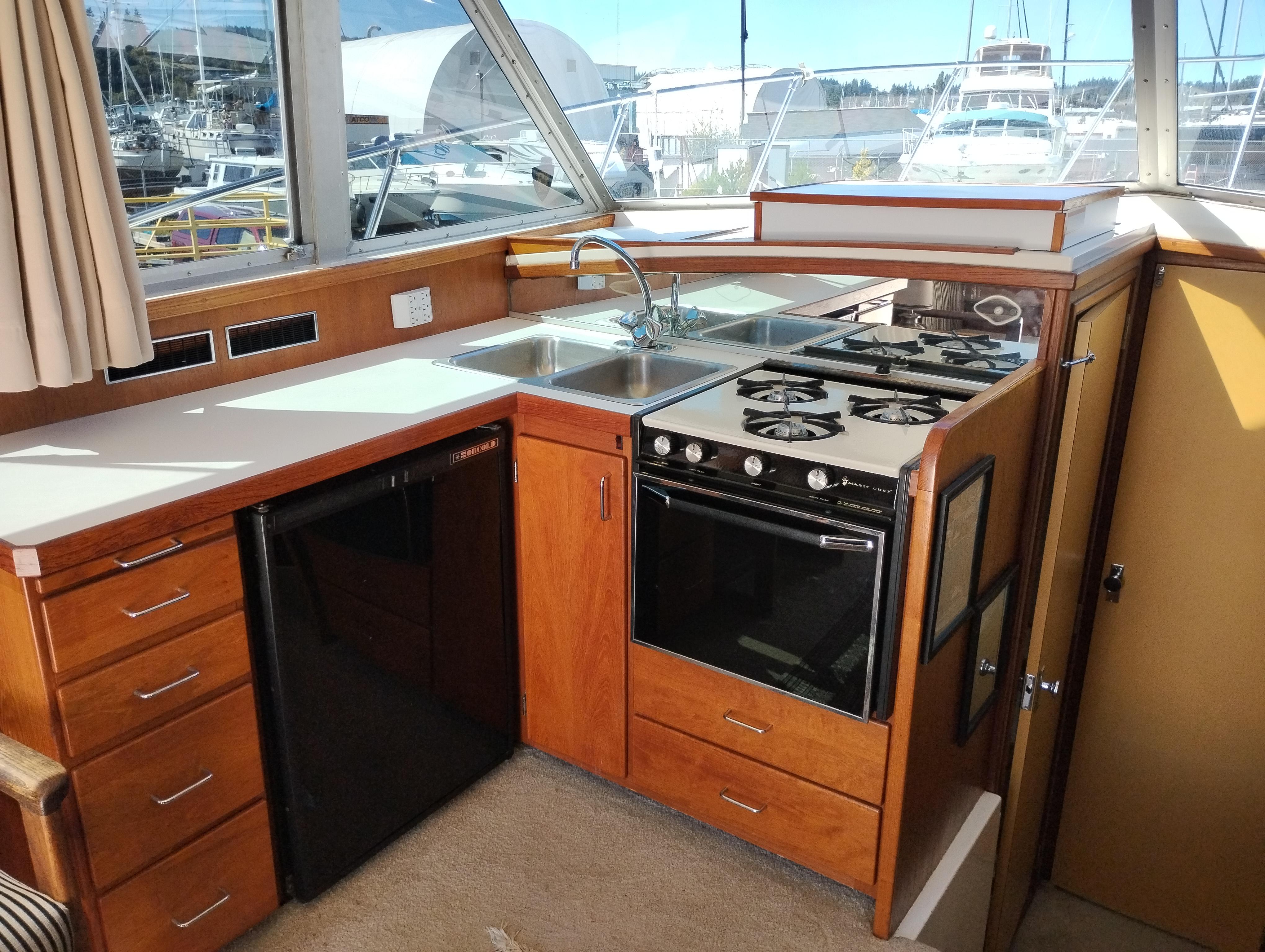 1978 Bertram 33 Convertible yacht kitchen with stove, sink, and wooden cabinetry.
