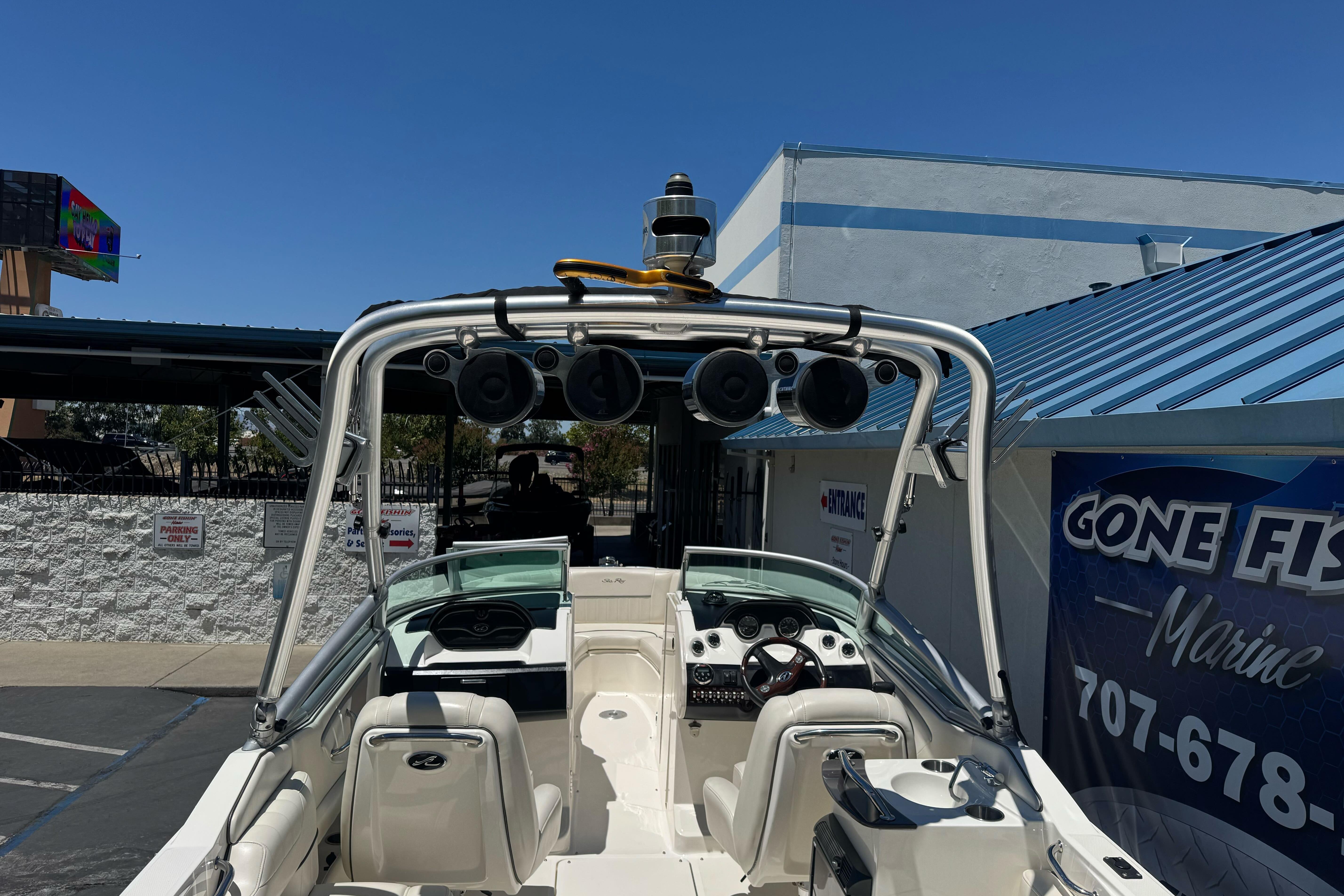 2007 Sea Ray SLX 250 boat with speakers, parked near a marine shop.