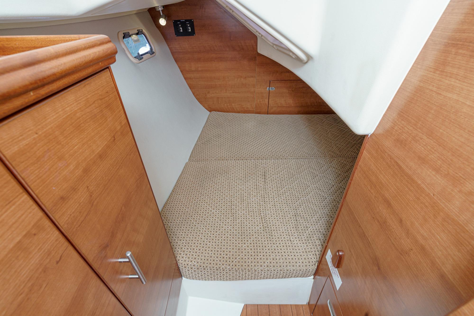 Cozy cabin interior of 2015 Hunter 33 sailboat with wooden finish and compact bed.