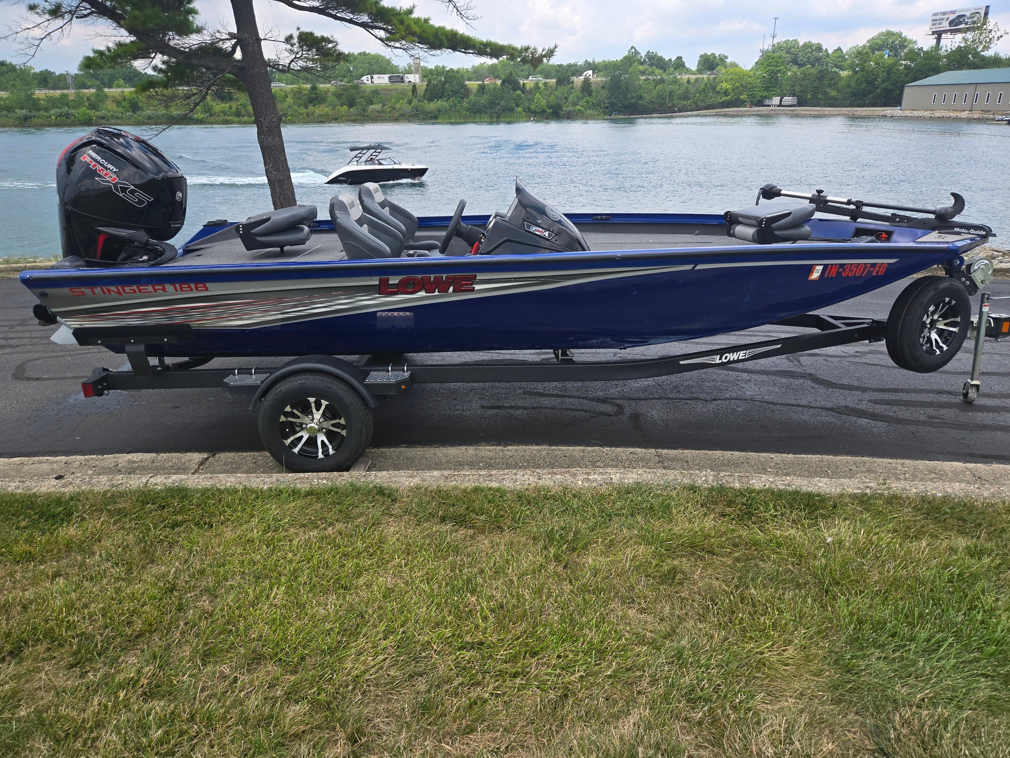 2021 Lowe Stinger 188 boat on trailer by a riverbank.