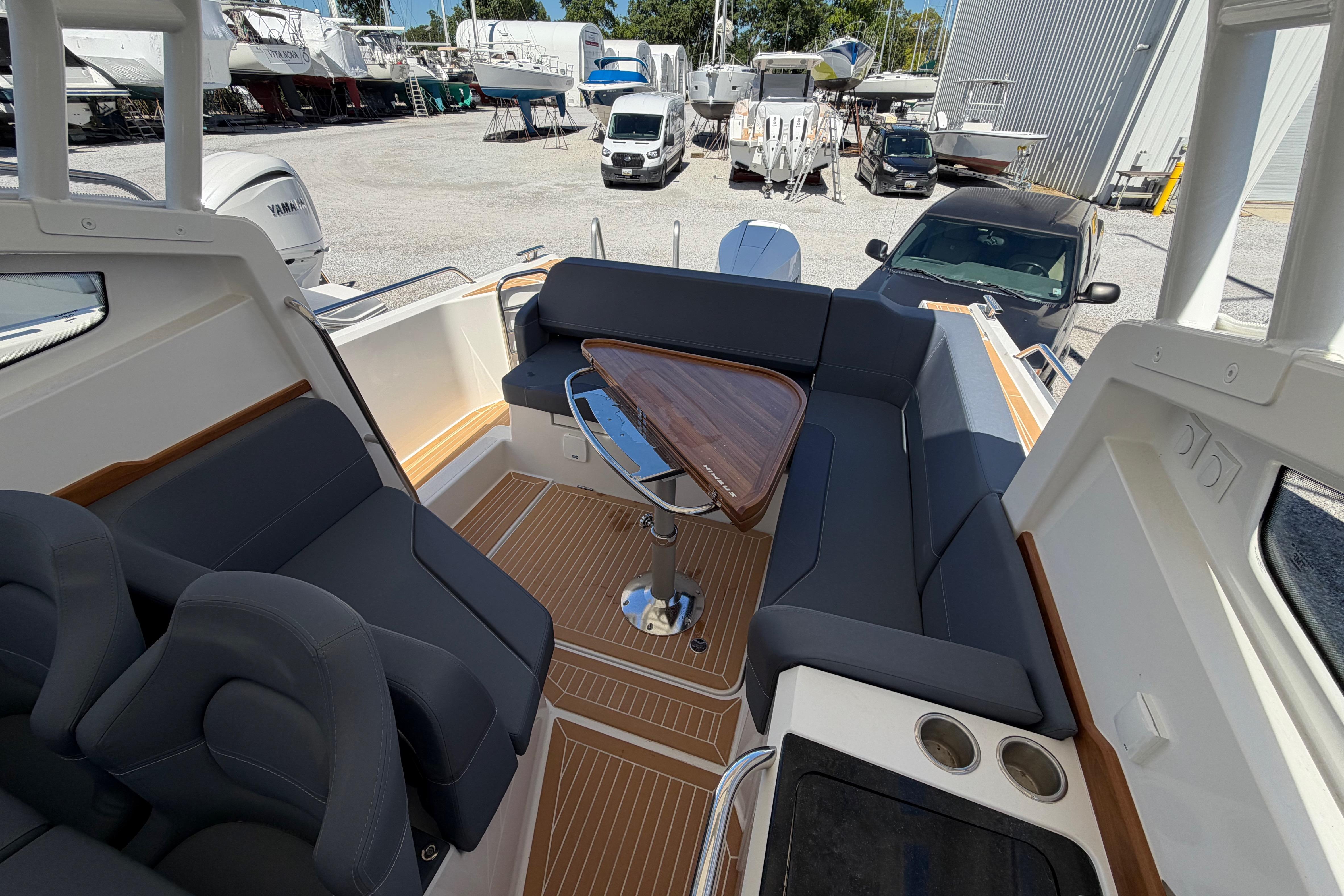2025 Nimbus Weekender 9 boat interior with sleek seating and wooden table in a marina setting.