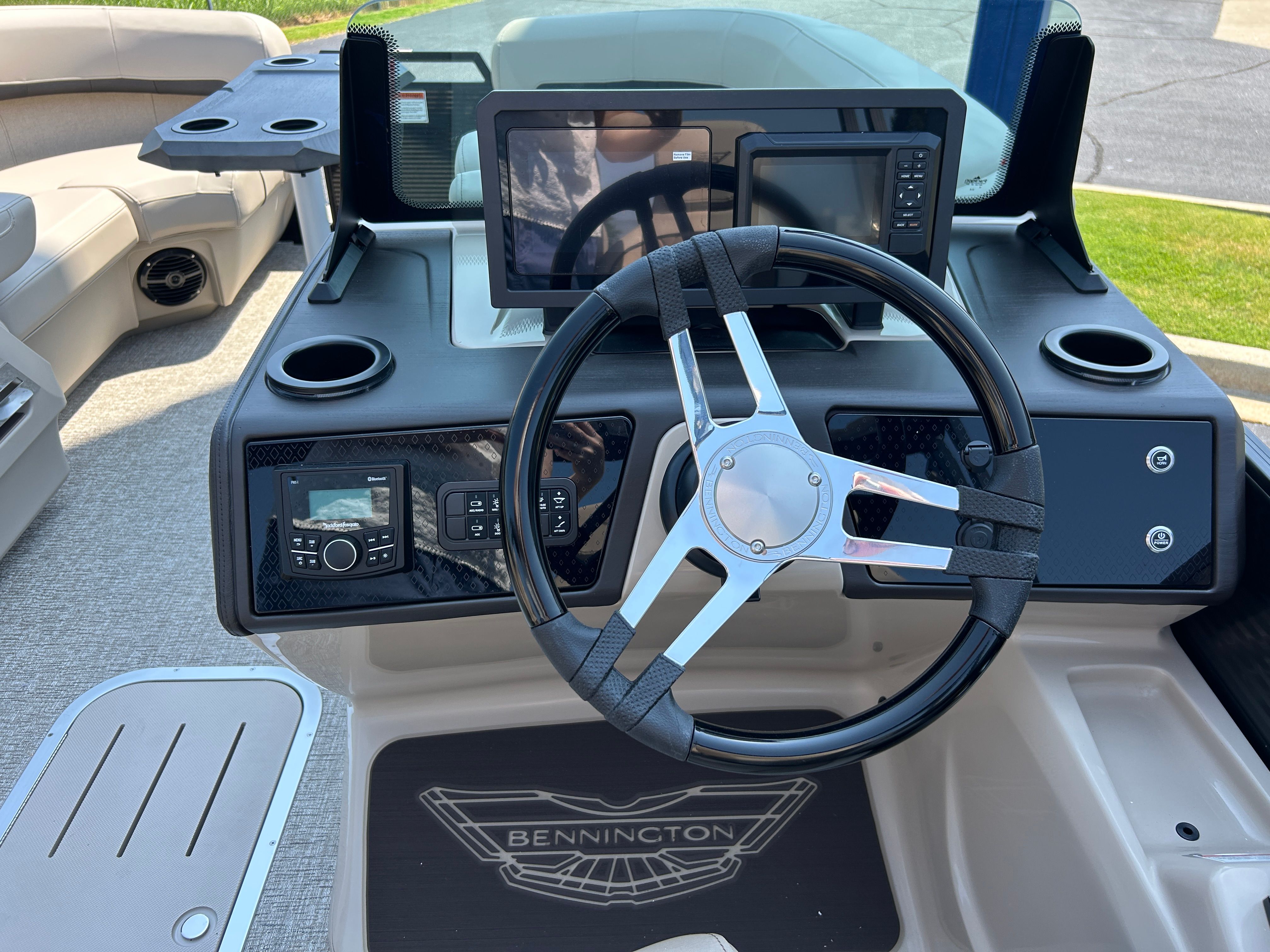 The image shows the helm of a Bennington 22 MFB boat with modern instruments and a sleek steering wheel.