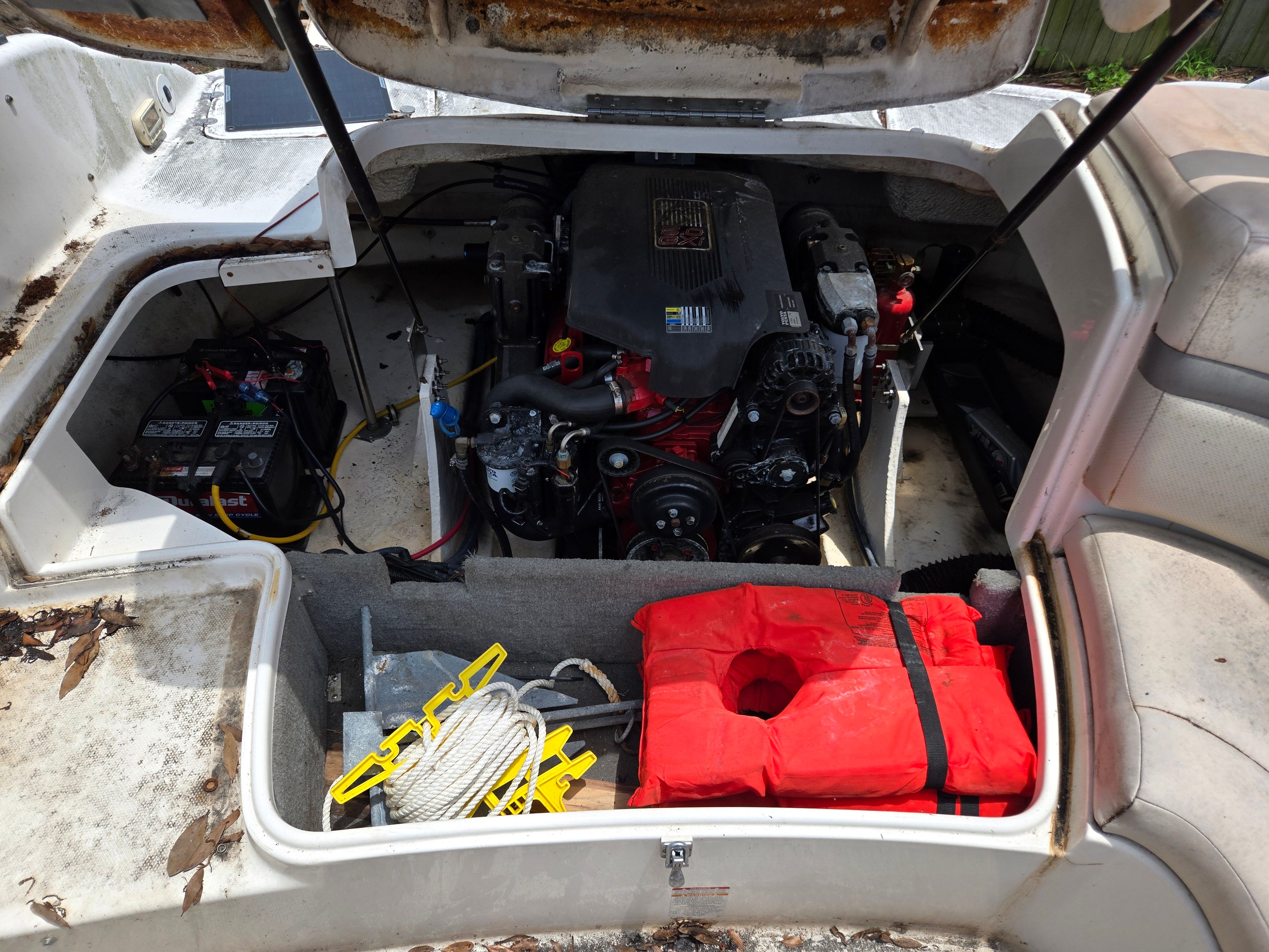 An open engine compartment of a 2006 Chaparral 220 SSi with engine, batteries, and life jacket.