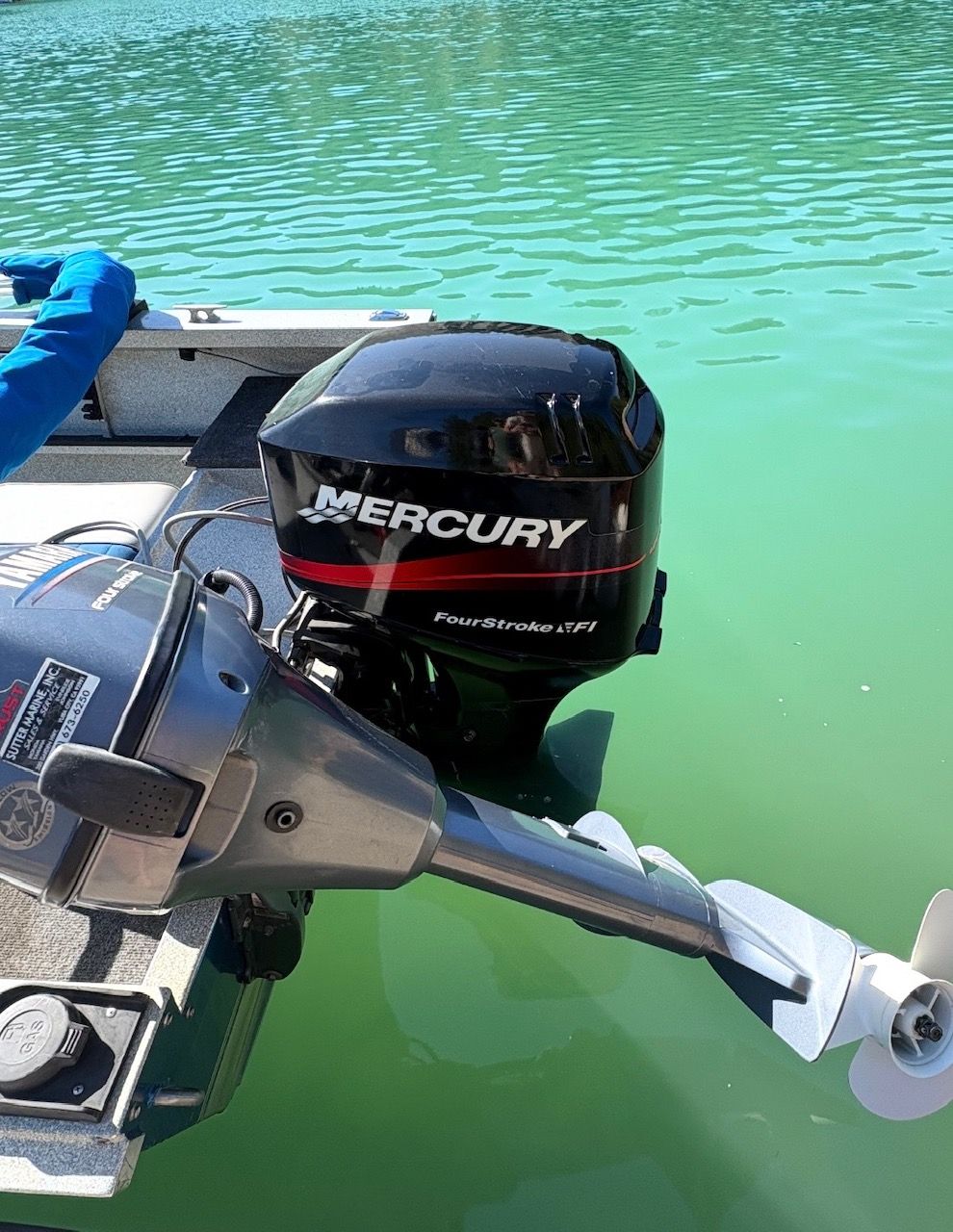 A Mercury FourStroke outboard motor on a boat in turquoise water.