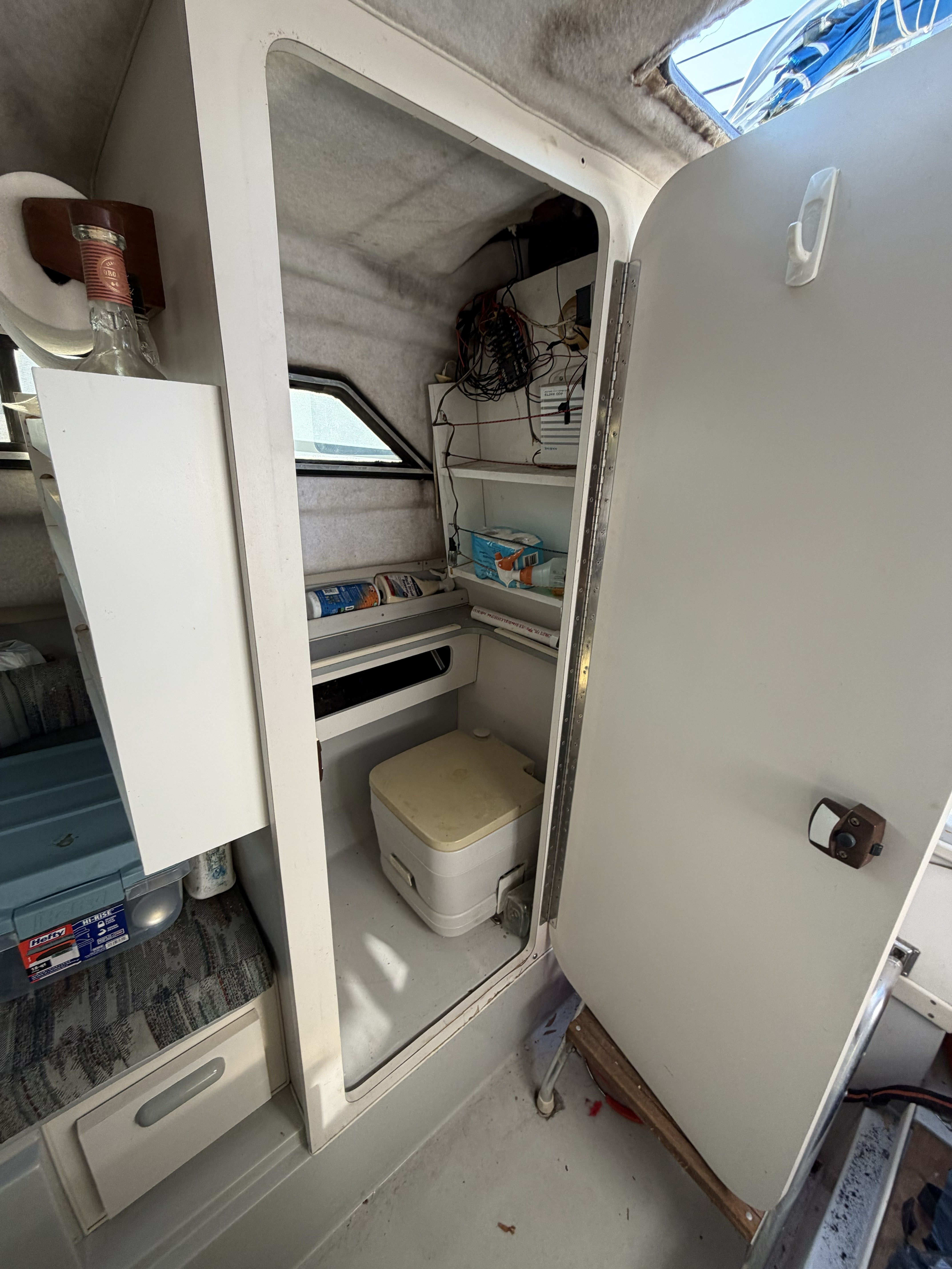 Interior of a 1989 Wellcraft 250 Sportsman featuring a small toilet and storage space.