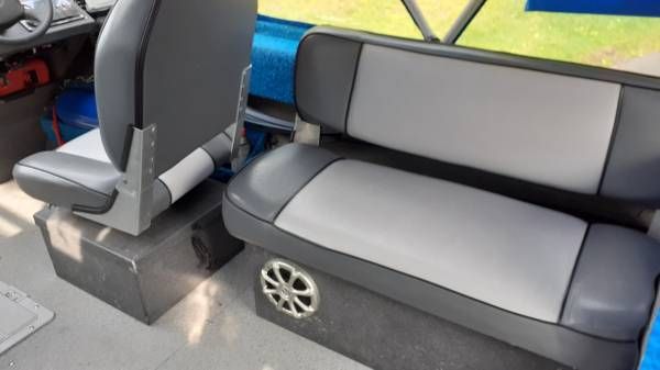 Interior of a boat with gray seats and a speaker.