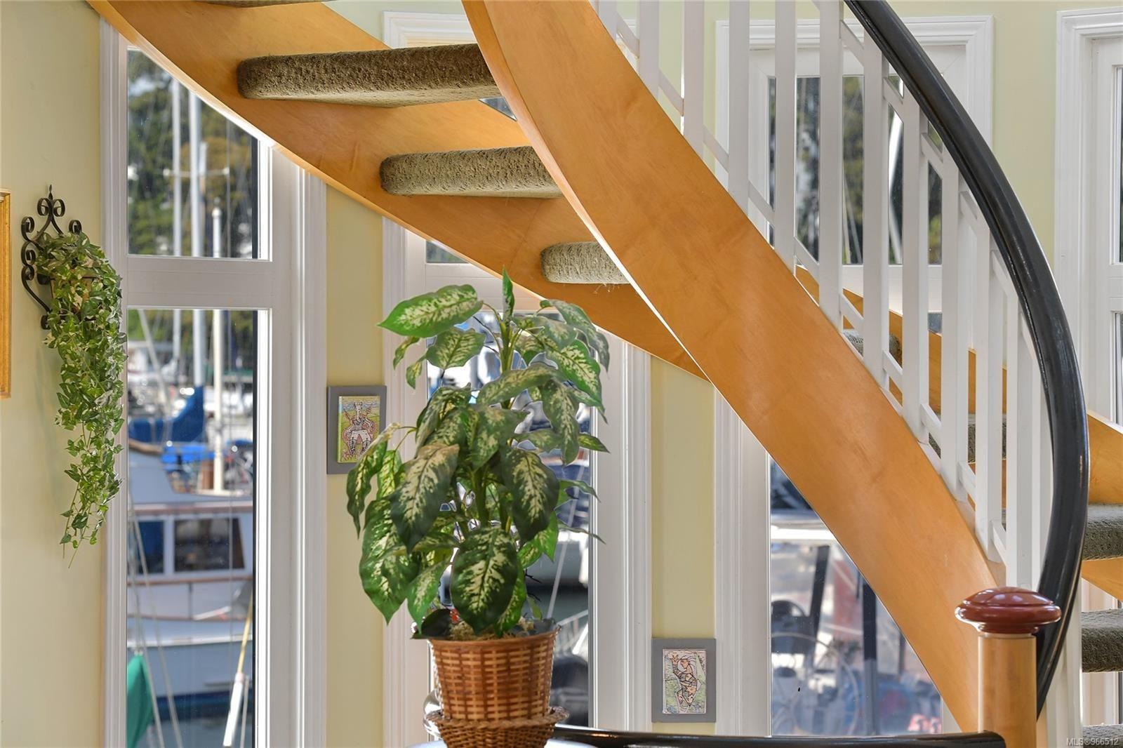 Curved wooden staircase in a 2005 custom float home with potted plants and marina view.