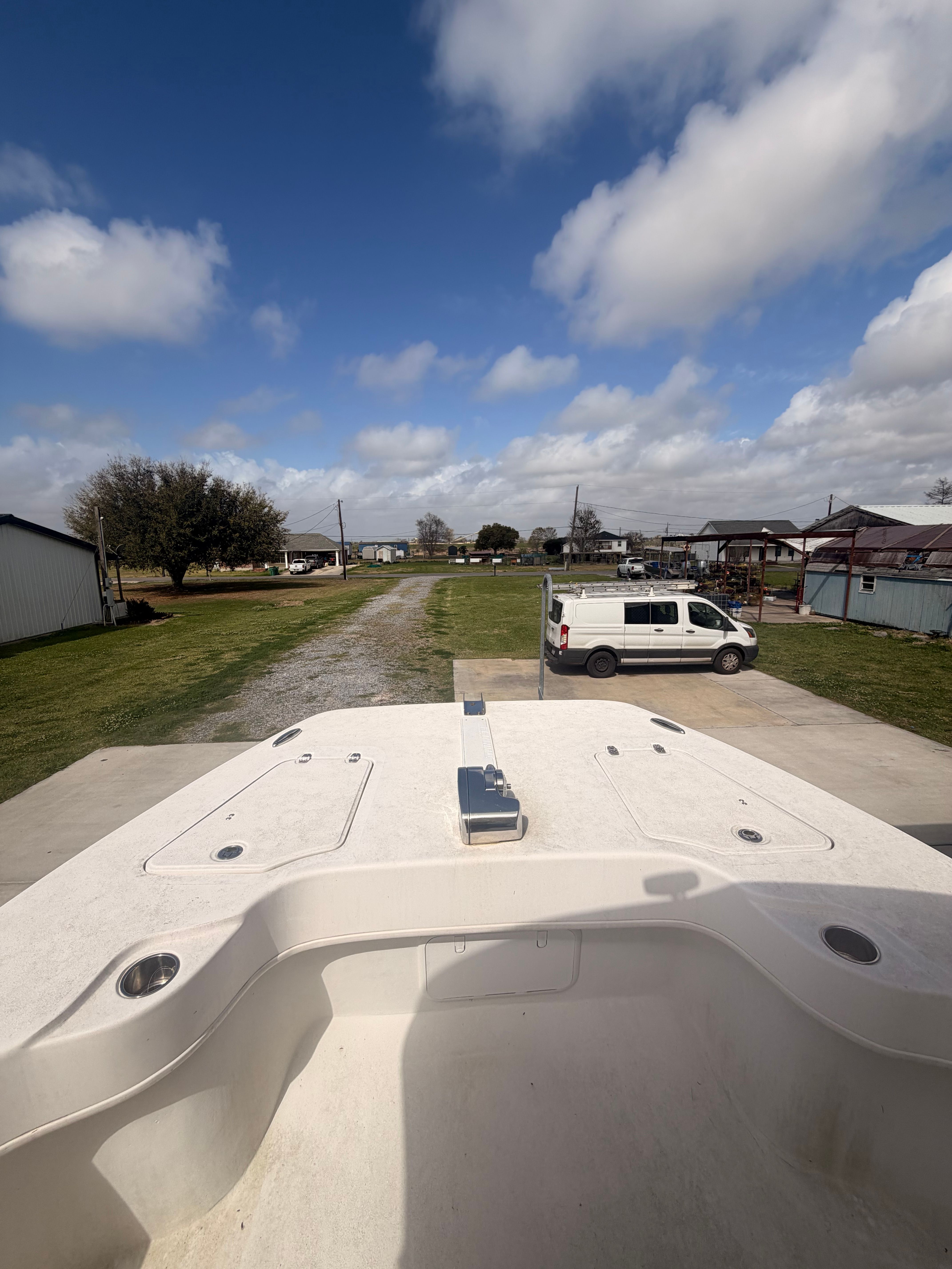 A Twin Vee Ocean Cat boat is on a trailer in a yard.