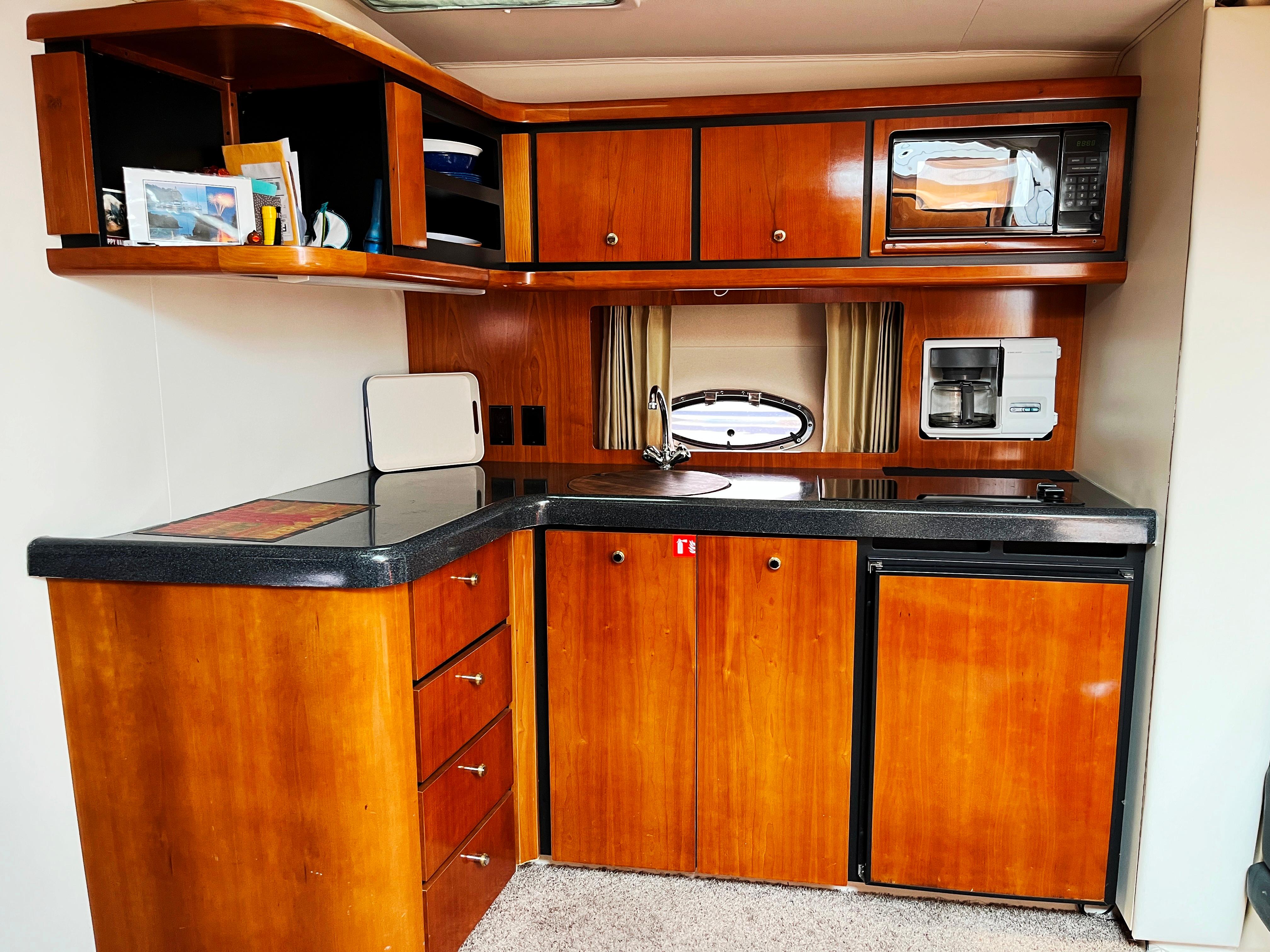 Trojan 400 Express Yacht 2000 kitchen with wood cabinets, microwave, and compact fridge.