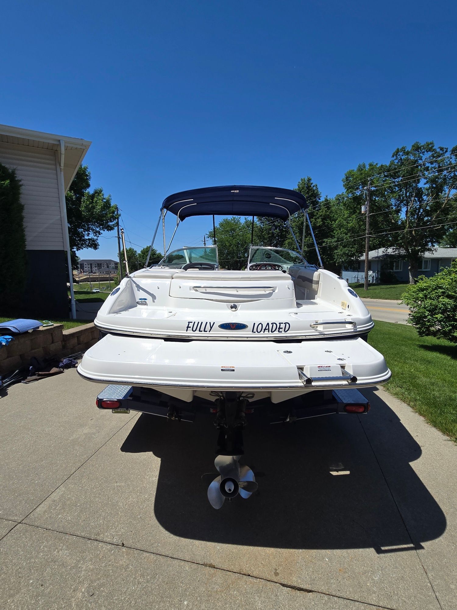 A white 2005 Chaparral 220 SSi boat on a trailer in a driveway.