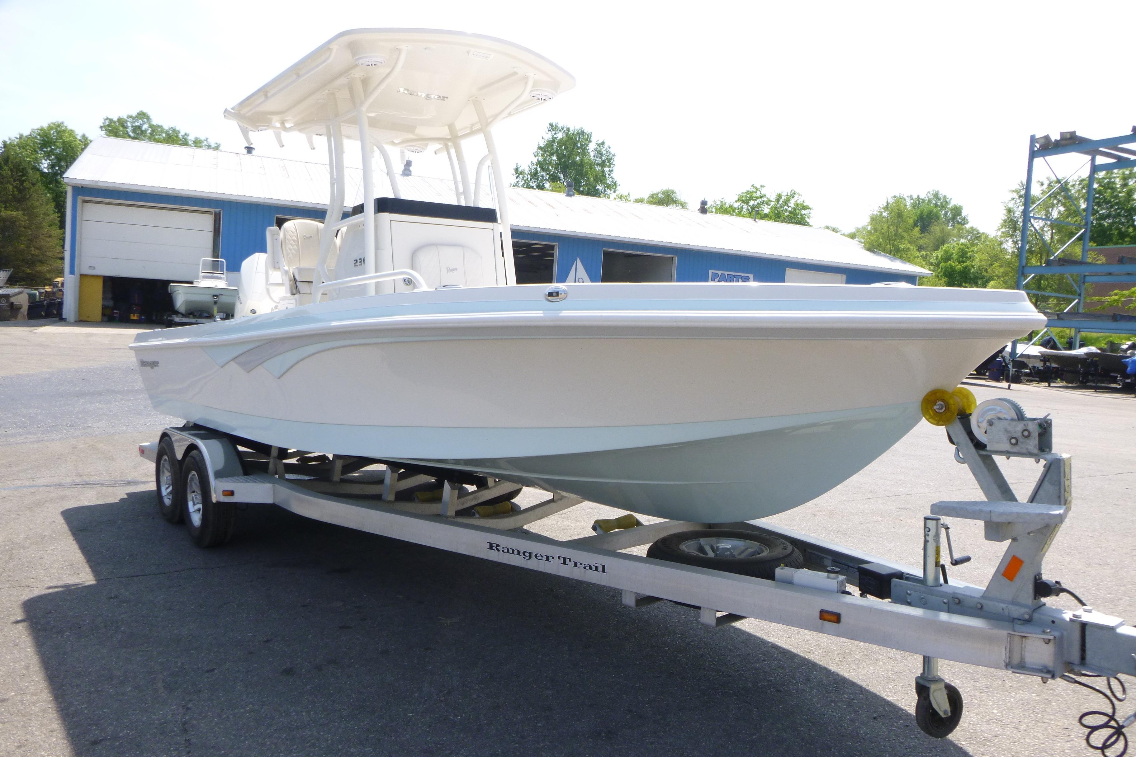 2024 Ranger 2360 Bay boat on trailer, parked outdoors near a blue building.
