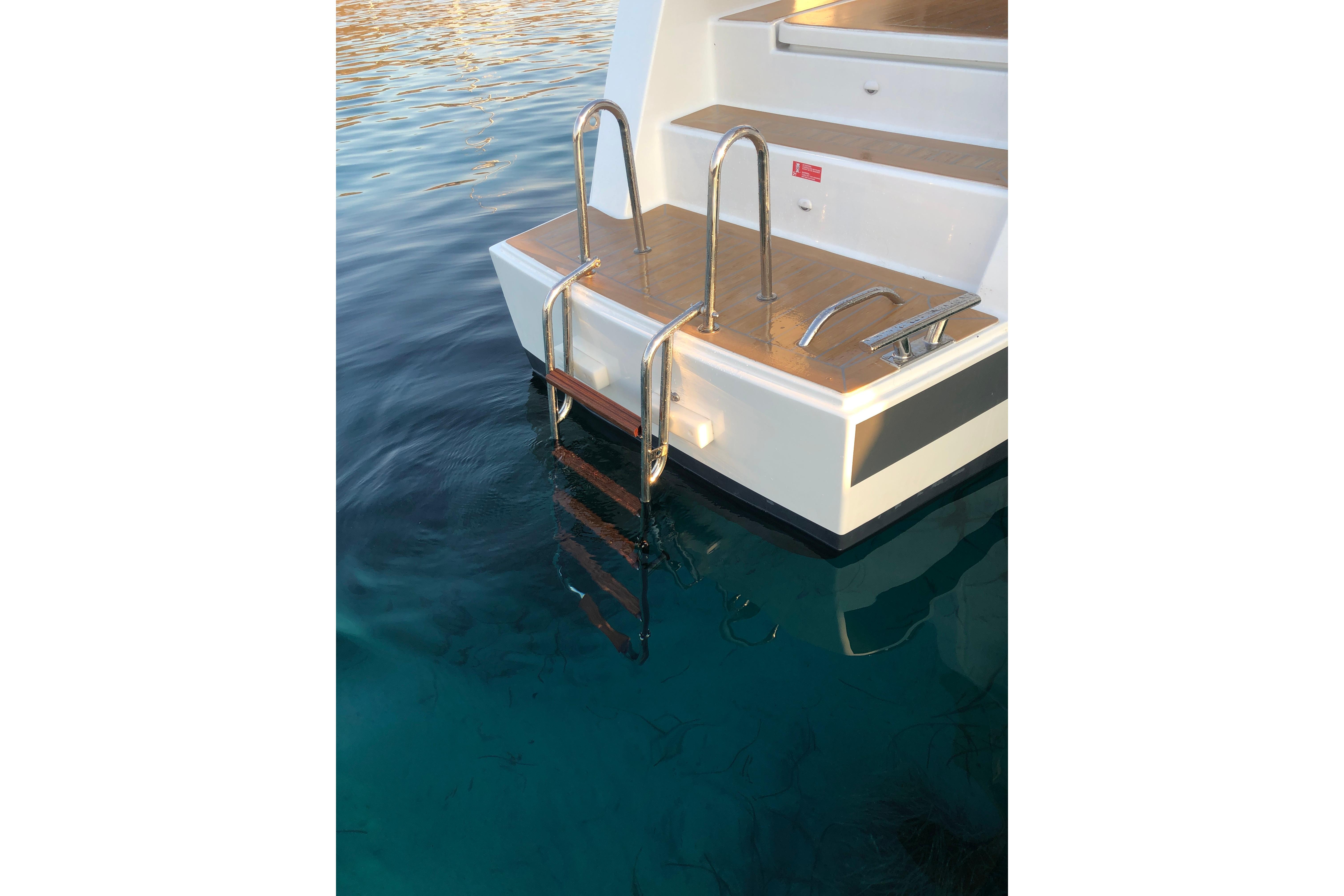 Stern view of 2020 Fountaine Pajot Saona 47 catamaran with swim ladder in clear water.
