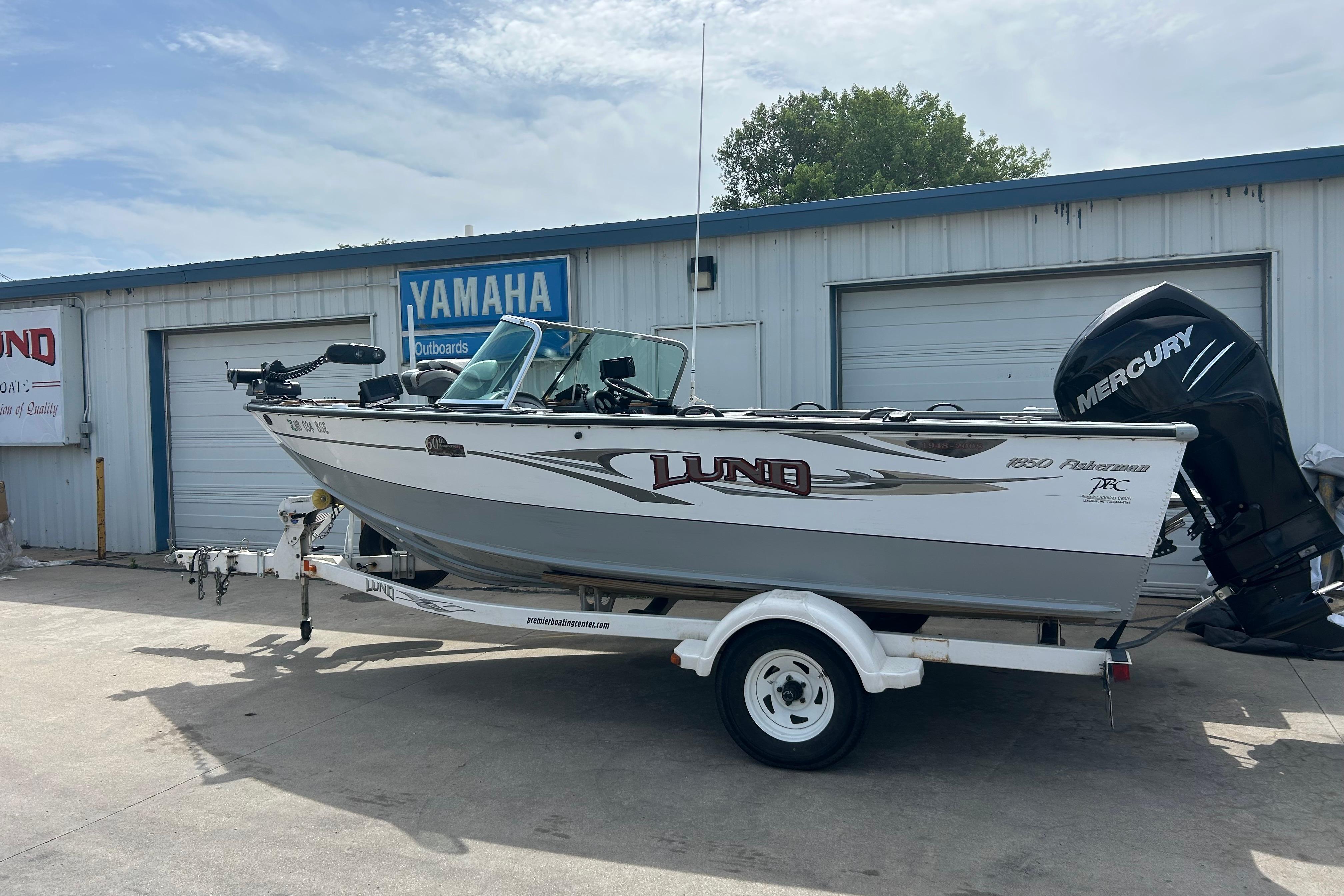 2008 Lund 1850 Fisherman boat on trailer, parked outside Yamaha dealership.
