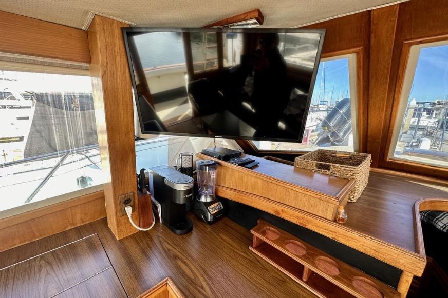 Interior of 1985 Egg Harbor 33 Sedan with TV, coffee maker, and blender on wooden counter.