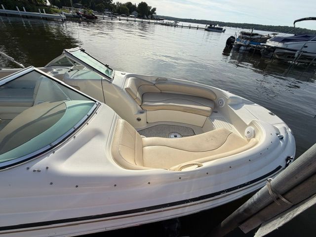 A 2001 Sea Ray 210 Sundeck on the water. It features beige upholstery and an open deck.