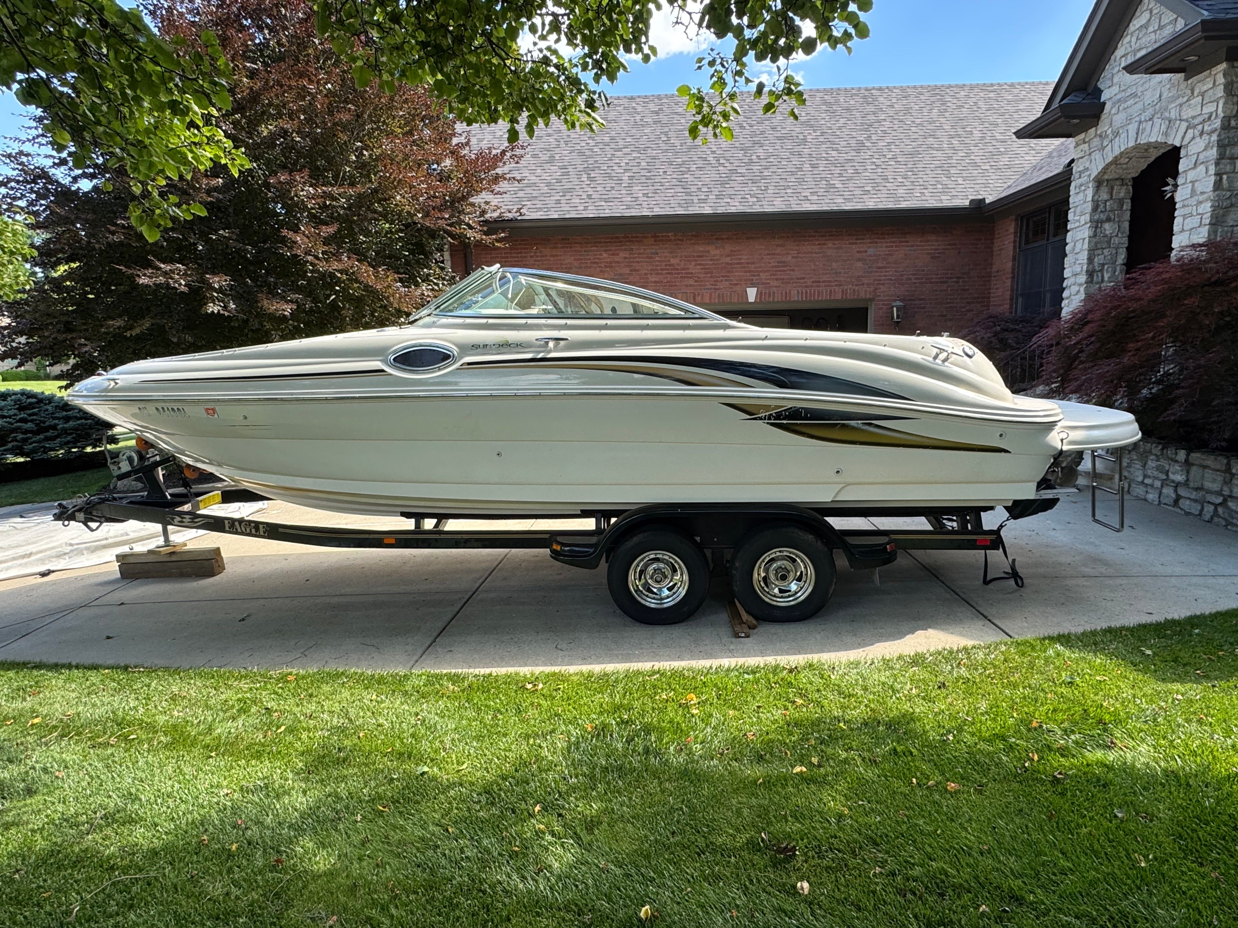 2001 Sea Ray 240 Sundeck boat on trailer in front of house.