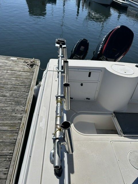 The image shows the stern of a boat with fishing rod holders and two outboard motors.