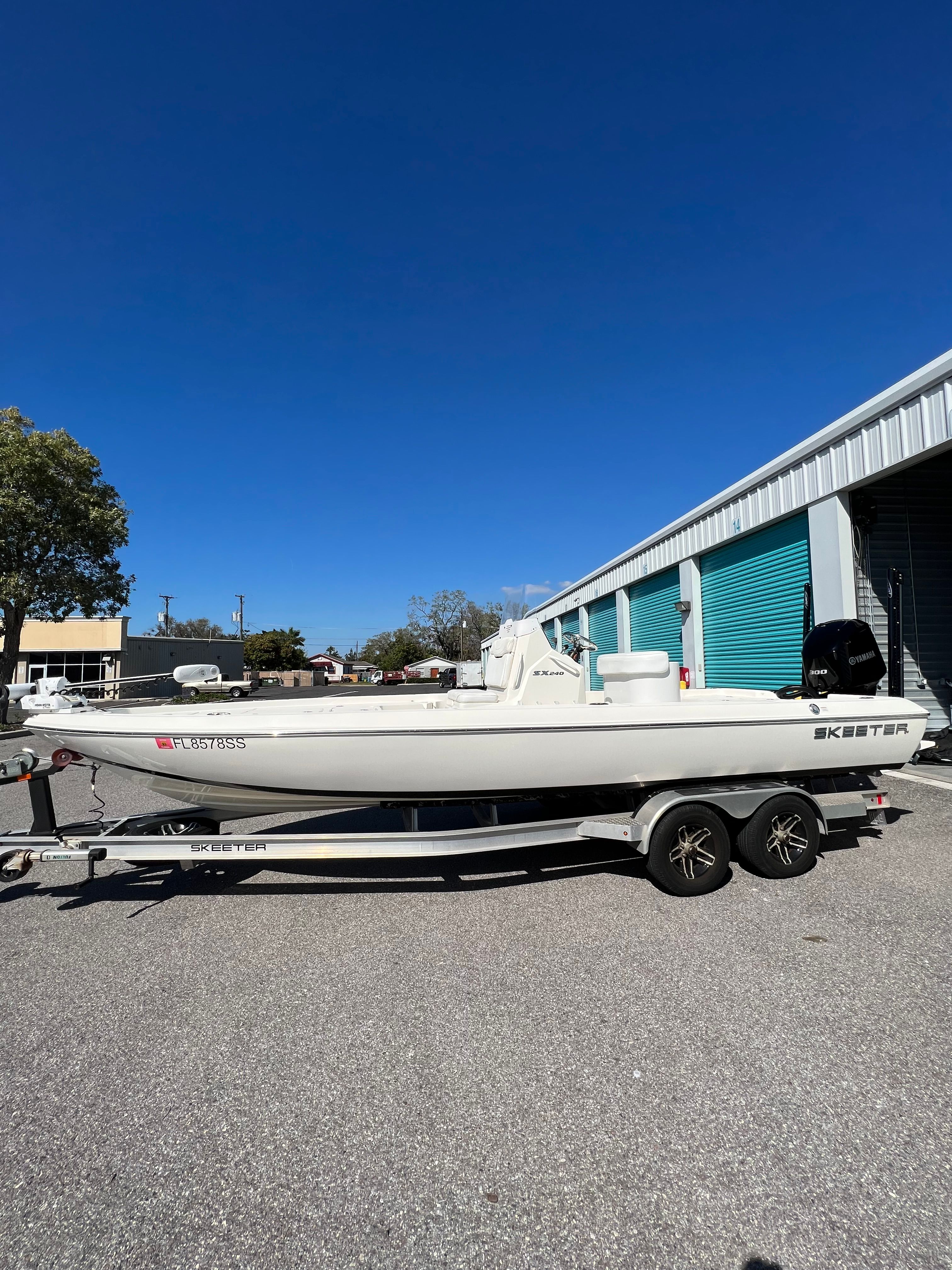 A white 2020 Skeeter SX240 boat on a trailer in front of a building.
