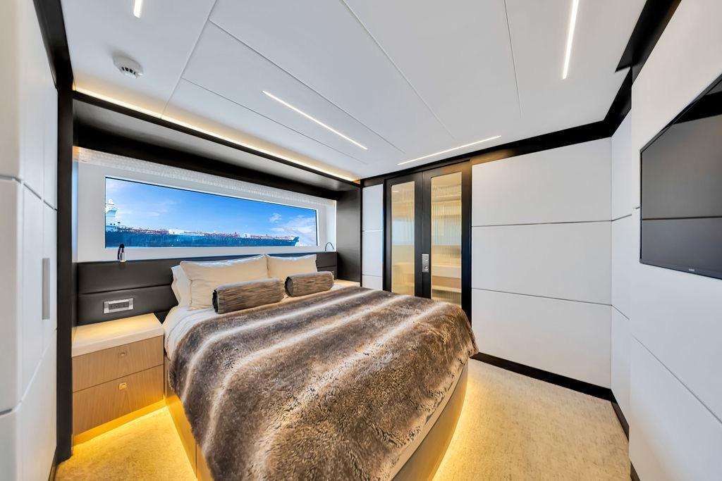Luxurious bedroom interior on 2020 Hargrave C92 yacht with ocean view window.