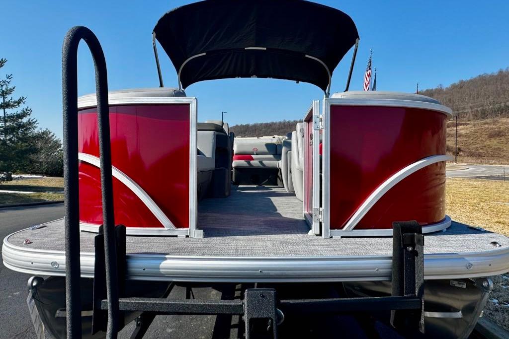 2026 Sun Tracker Party Barge 20 DLX pontoon boat with red exterior, parked outdoors.