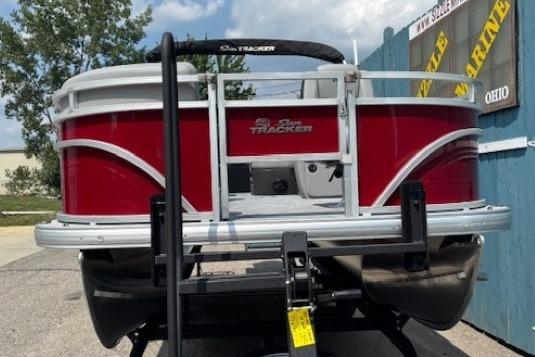 2026 Sun Tracker SportFish 20 DLX pontoon boat with red exterior, displayed outdoors.