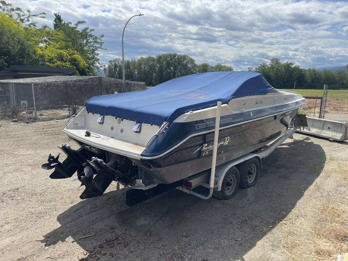 1987 Sea Ray PACHANGA boat on trailer with blue cover, parked outdoors.