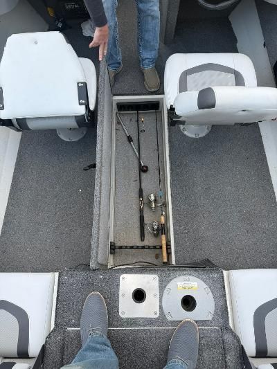 Interior view of a boat with two seats and a storage compartment for fishing rods.
