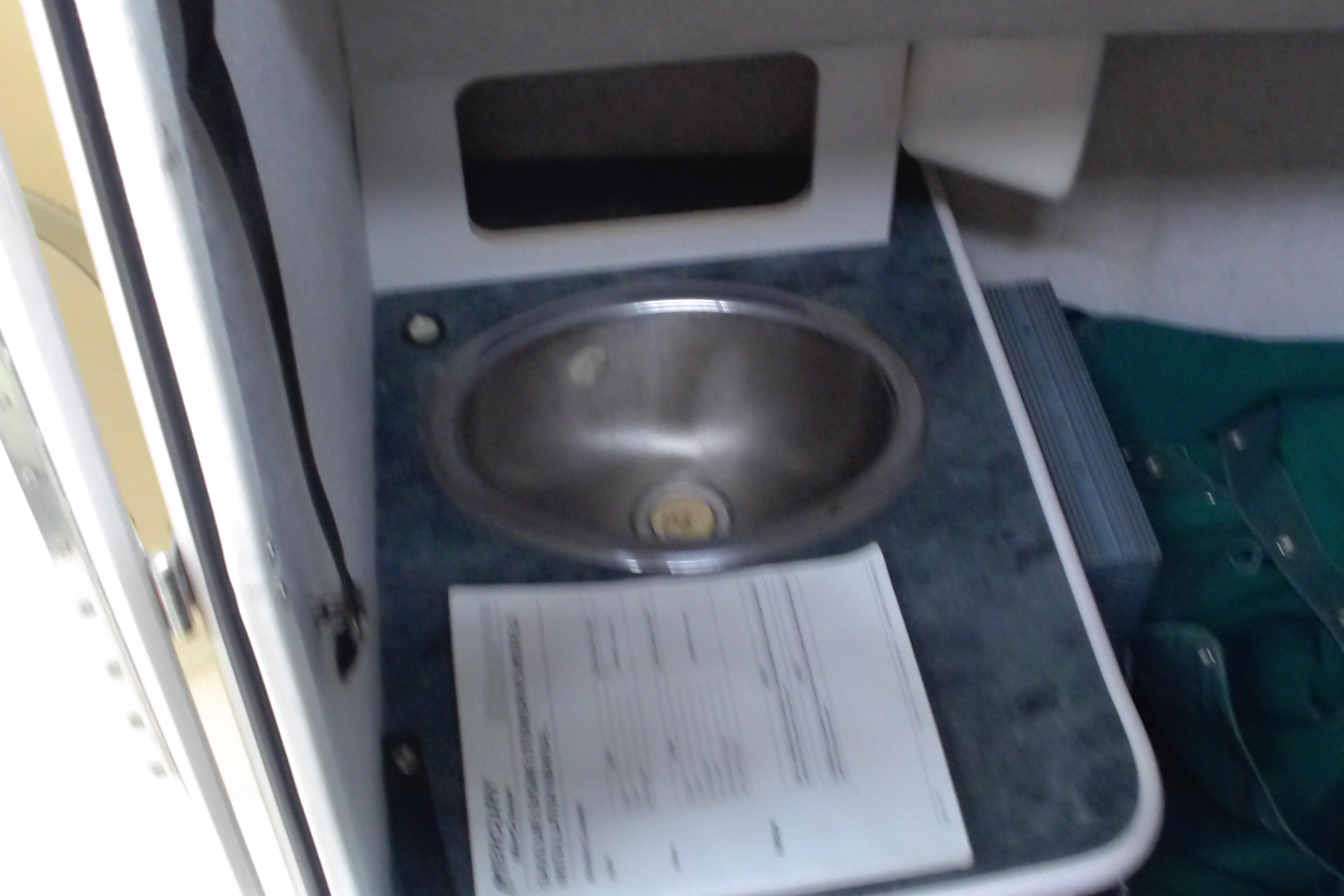 2004 Trophy 2352 Walkaround boat interior with sink and document on counter.