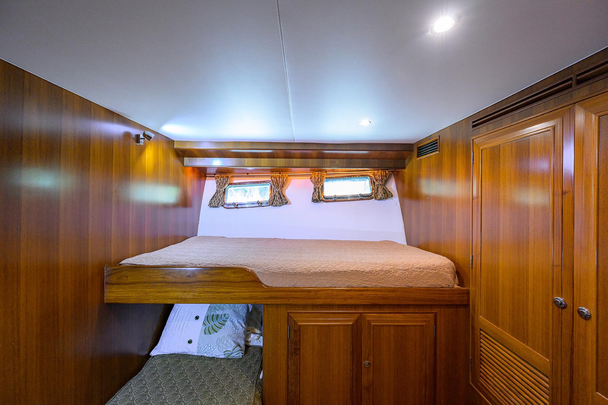 Luxurious wooden cabin interior of 2001 Ocean Alexander 602 yacht with cozy bedding.