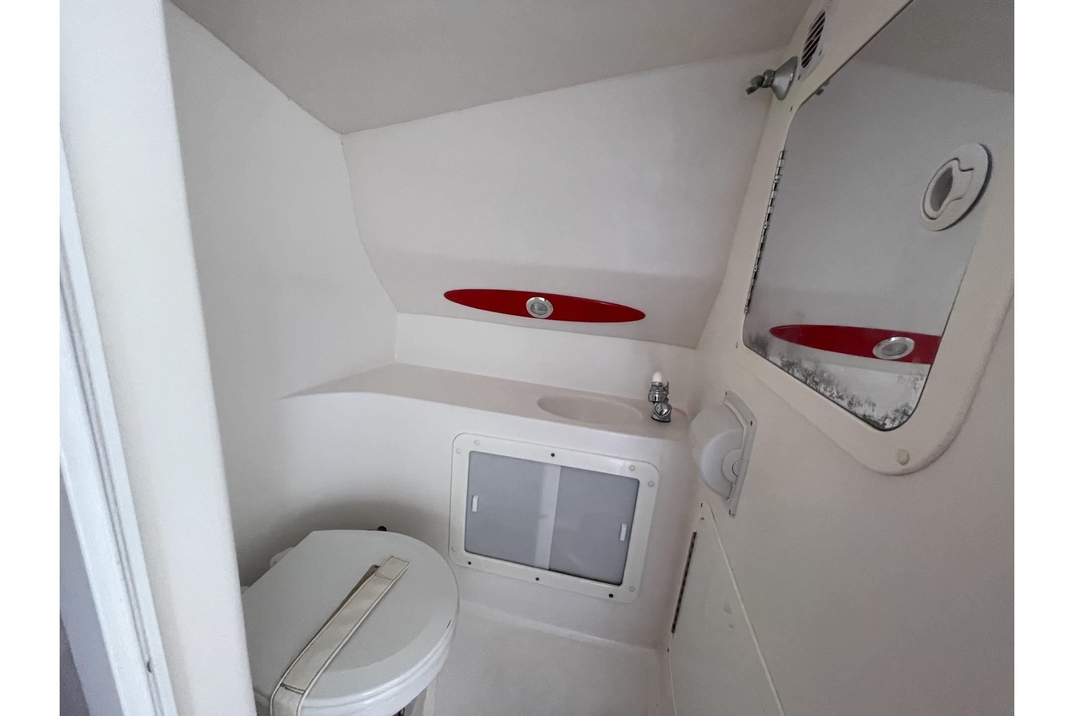 Compact bathroom in a 2006 Sonic 386 boat, featuring a toilet and sink.