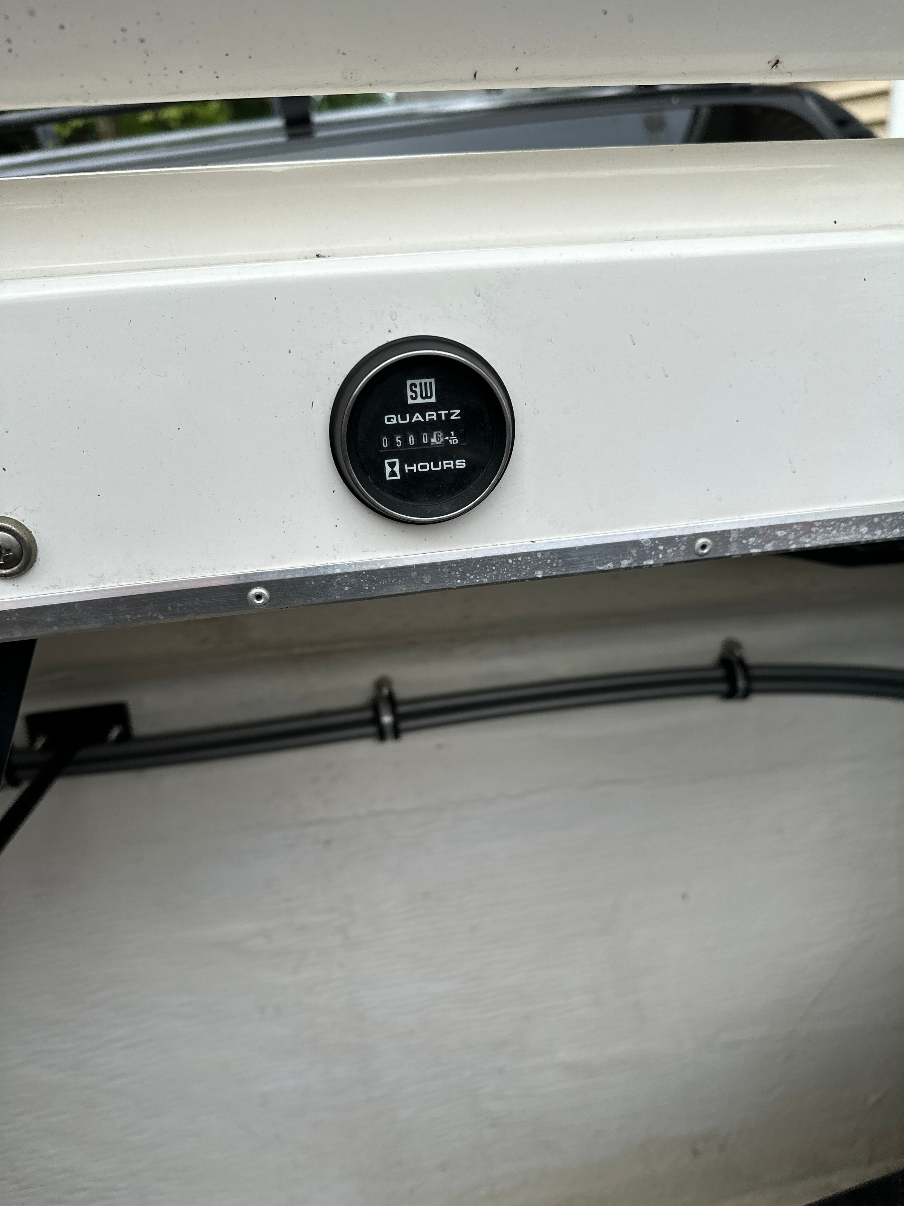 Close-up of an hour meter on a boat, surrounded by white surfaces.