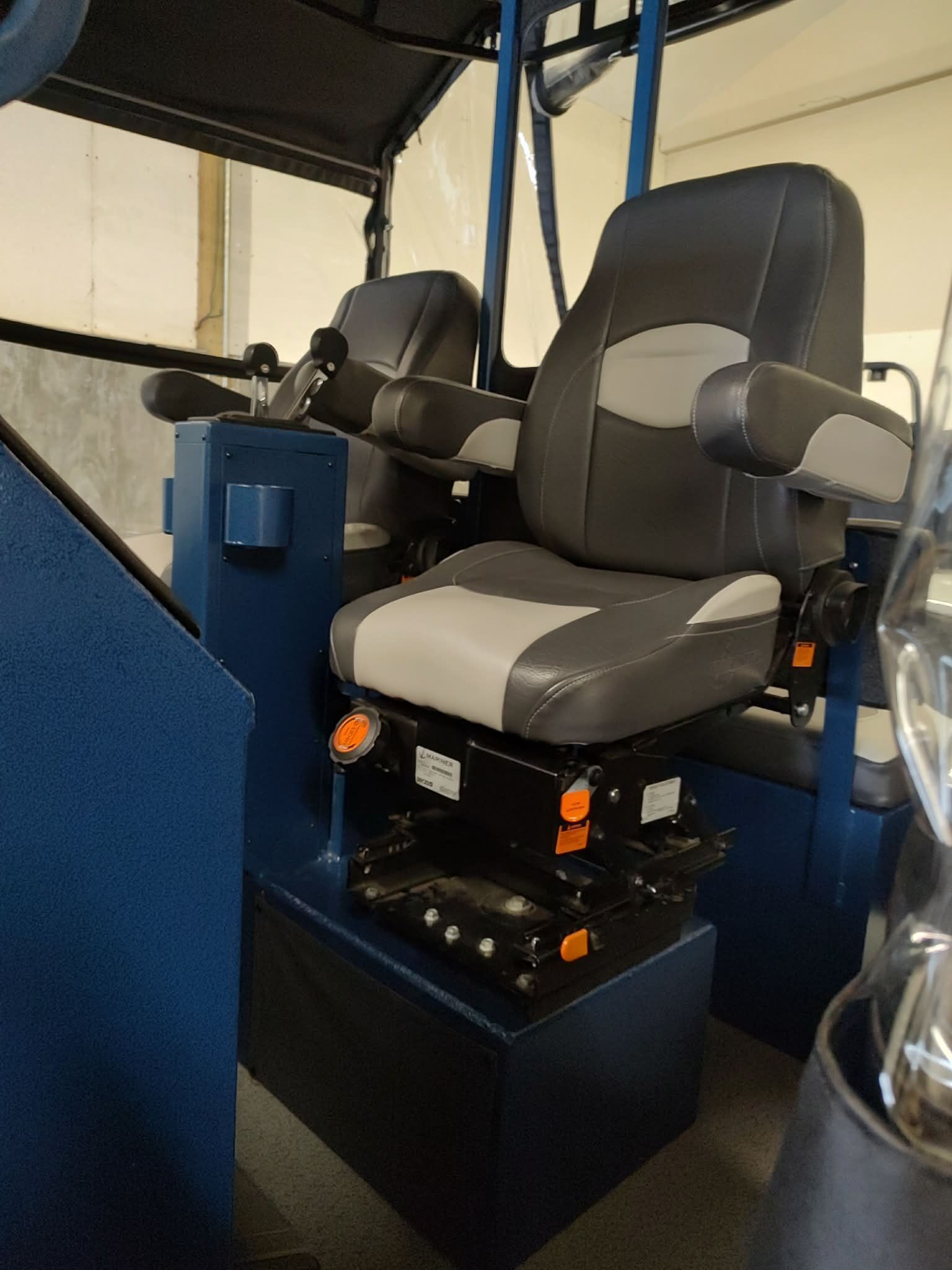 Two cushioned seats with armrests in a boat, surrounded by blue metal structures.