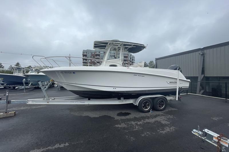2012 Boston Whaler 250 Outrage boat on trailer, parked outdoors on a cloudy day.