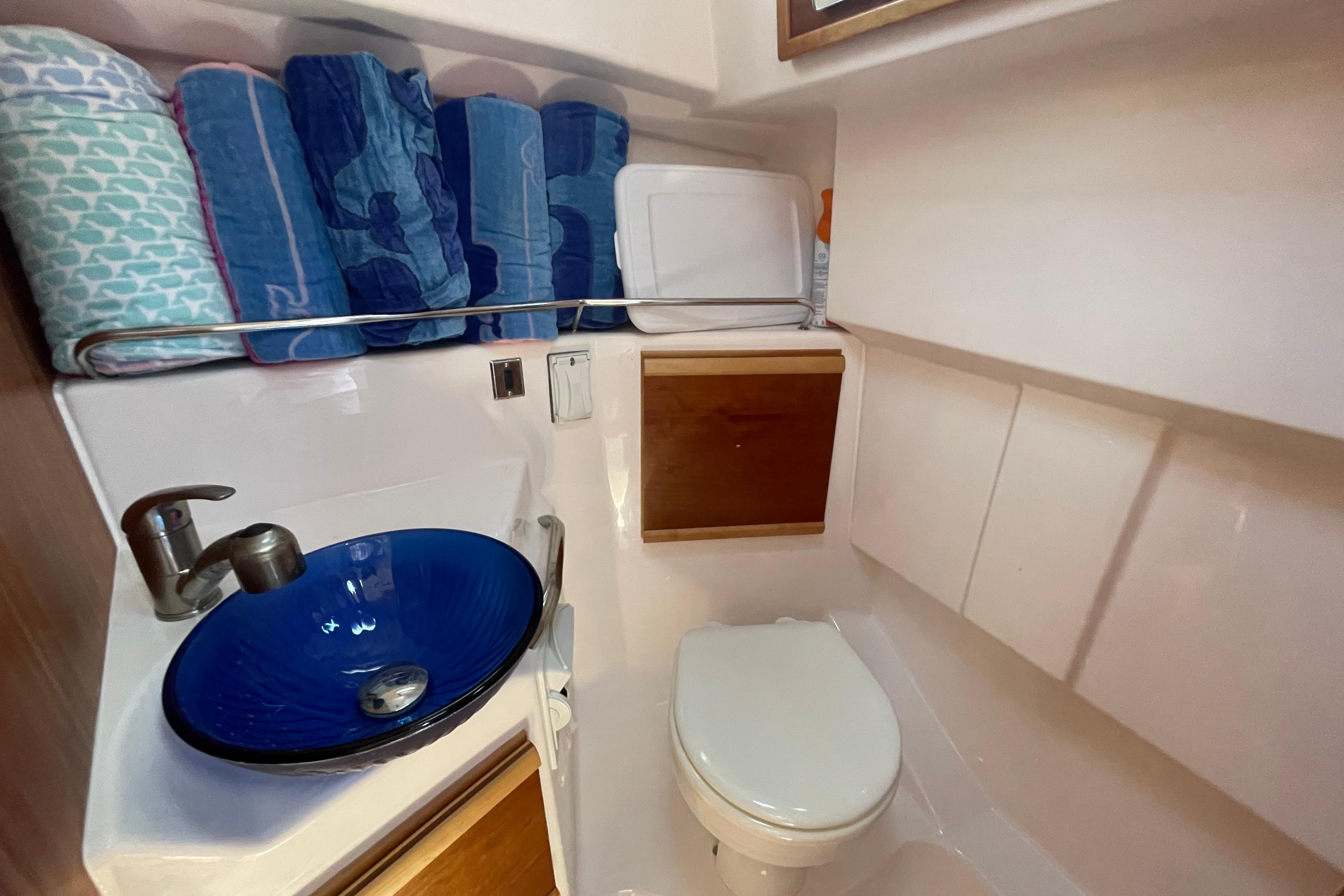 2019 Cutwater C-28 boat bathroom with blue sink, toilet, and storage shelves.