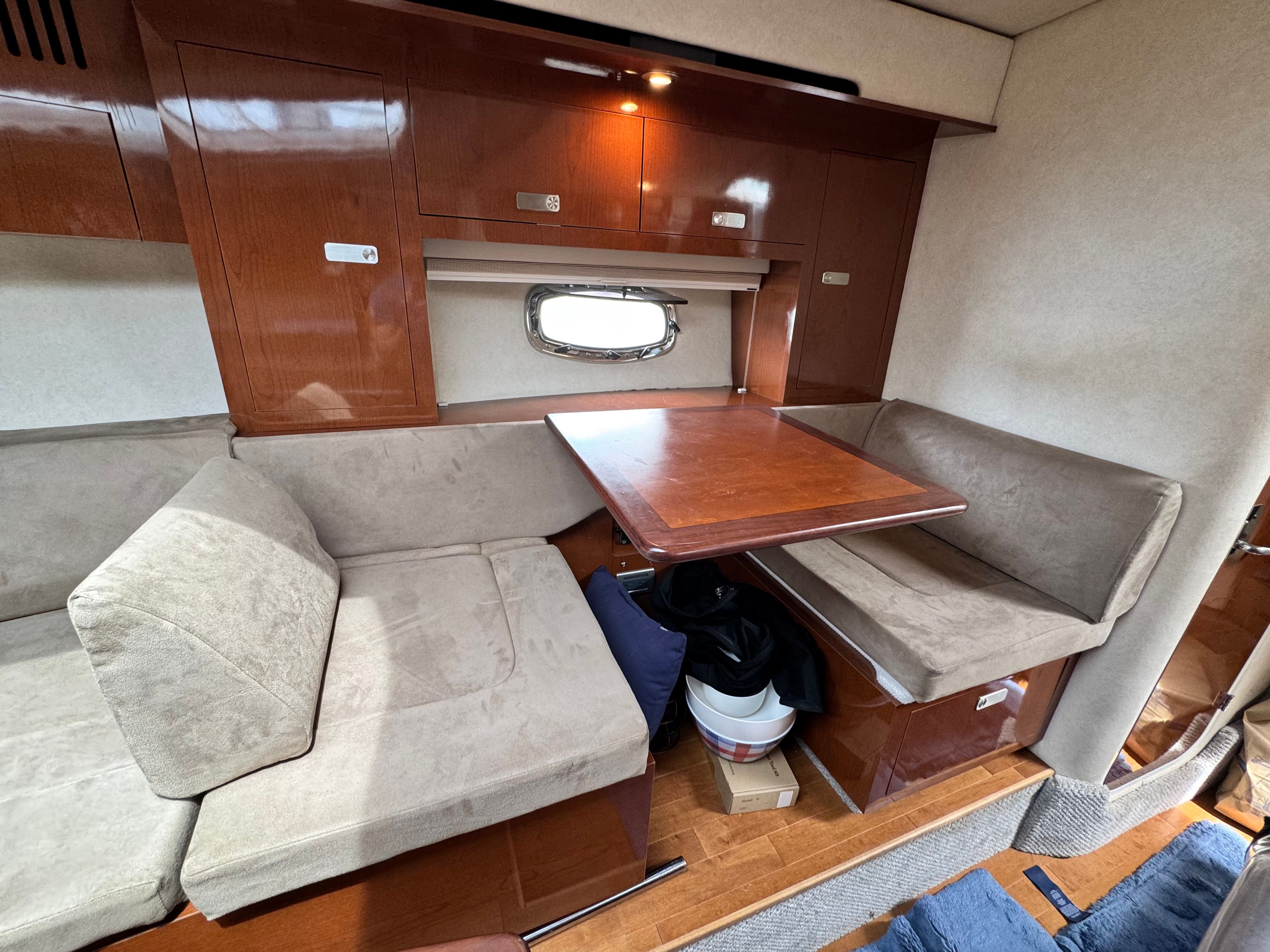 Interior of a Sea Ray Sundancer 310 with a cozy seating area and wooden table.