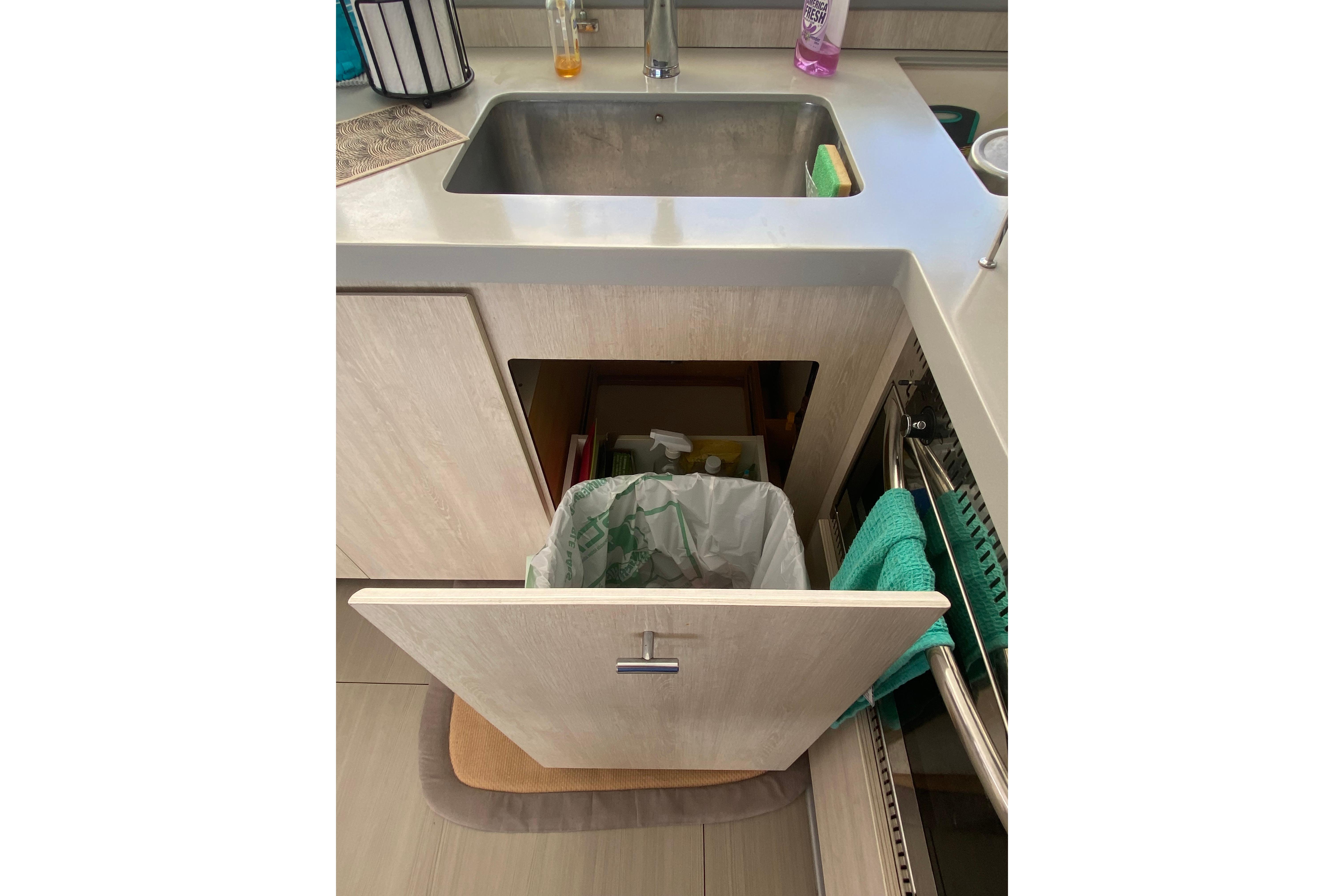 Modern kitchen sink with open cabinet, revealing trash bin and cleaning supplies. Leopard 40, 2017 model.