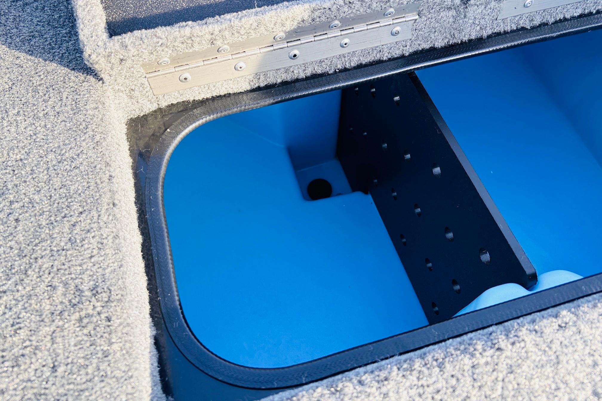 2025 Tracker Savage 215 boat storage compartment with blue interior and carpeted edges.