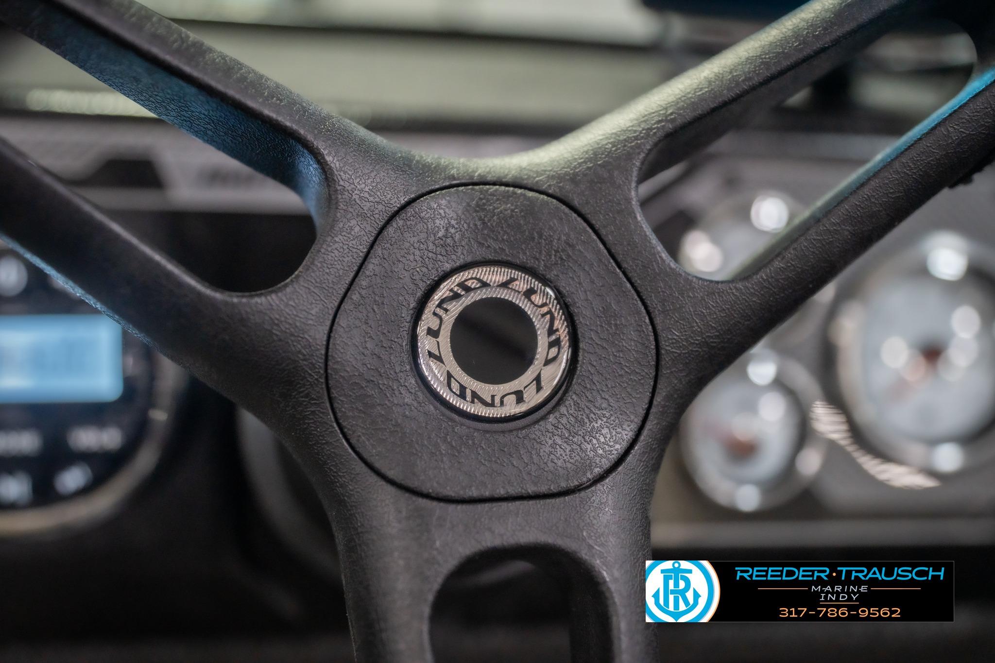 Steering wheel of 2026 Lund 2075 Impact XS boat, featuring brand logo and dashboard.