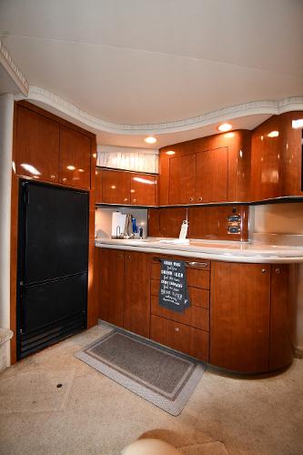 Interior of 2003 Sea Ray 460 Sundancer yacht with wooden cabinetry and modern kitchen amenities.