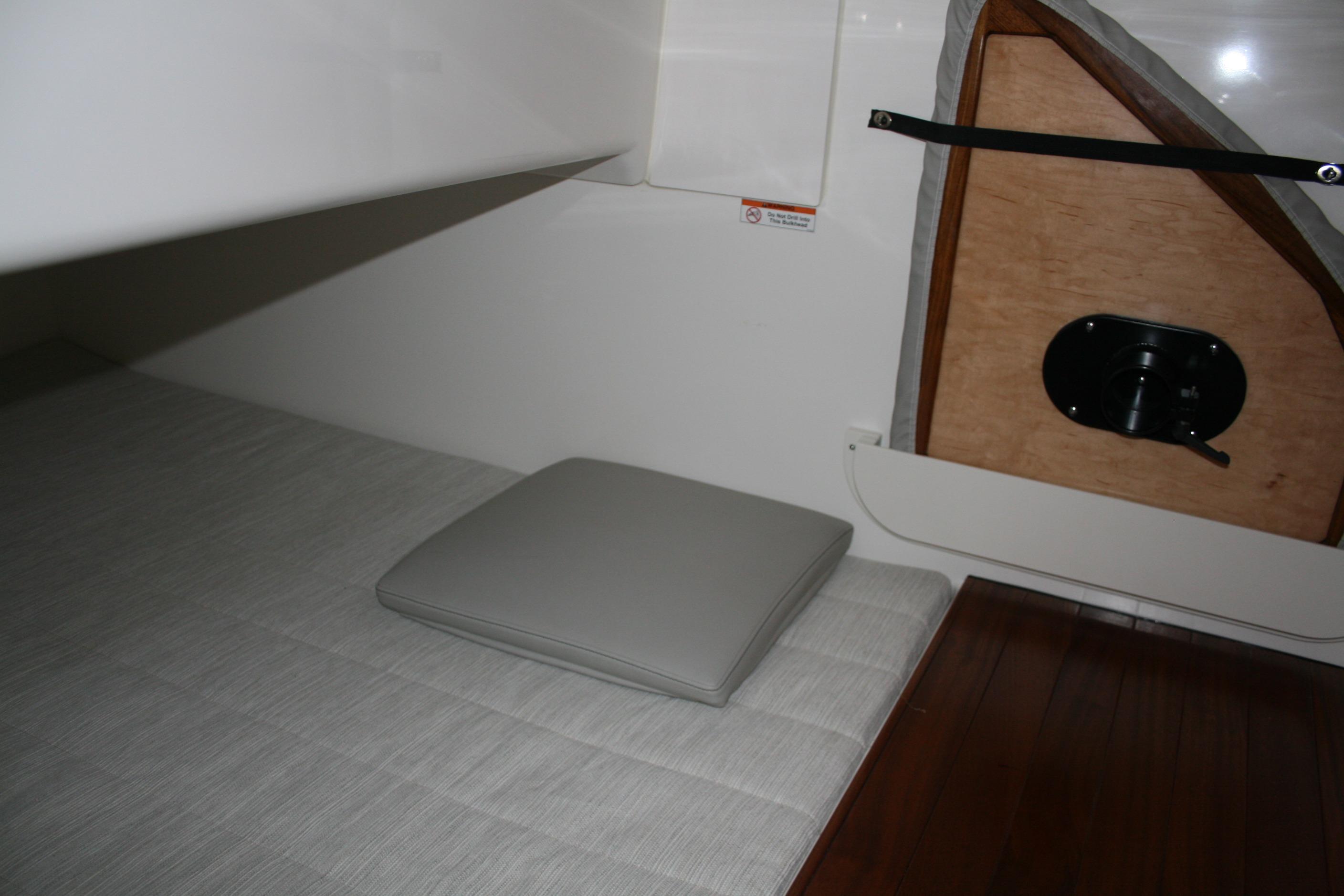 Interior cabin of 2025 Pursuit OS 405 Offshore boat, featuring cushioned seating and wooden accents.
