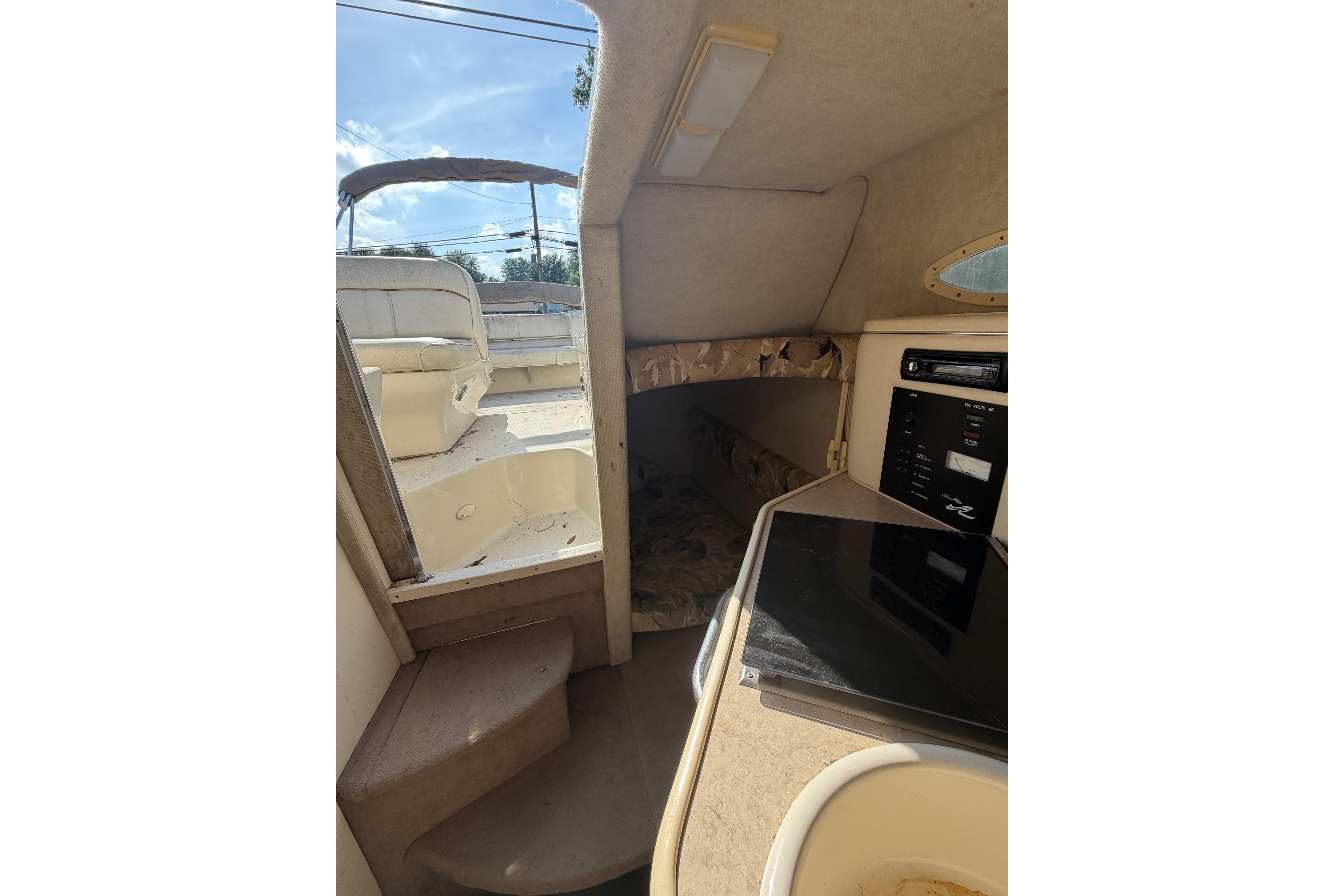 Interior view of 1999 Sea Ray 240 Sundancer cabin with kitchenette and seating area.