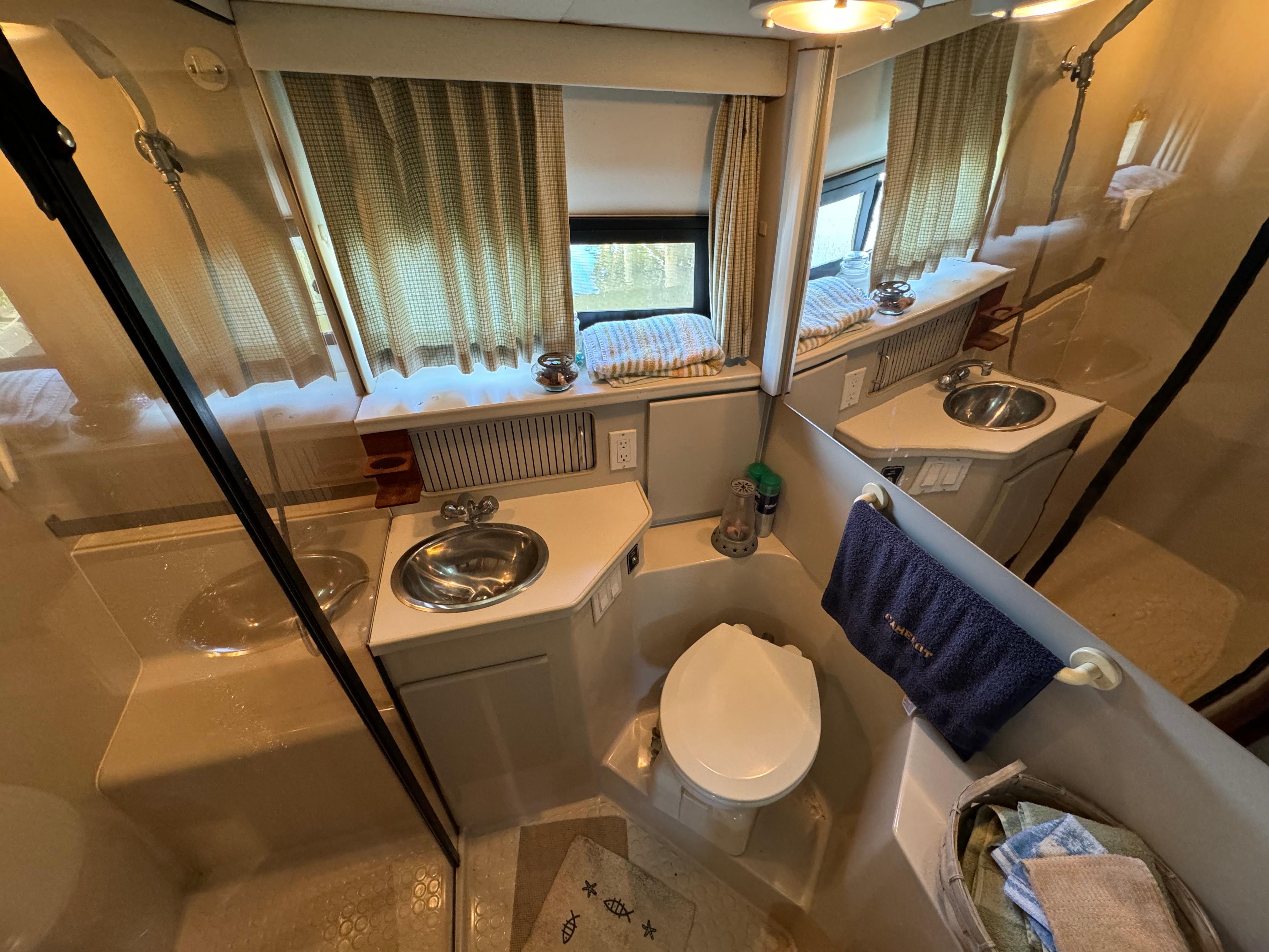1991 Carver 33 Aft Cabin bathroom with sink, toilet, and shower, featuring curtains and mirror.