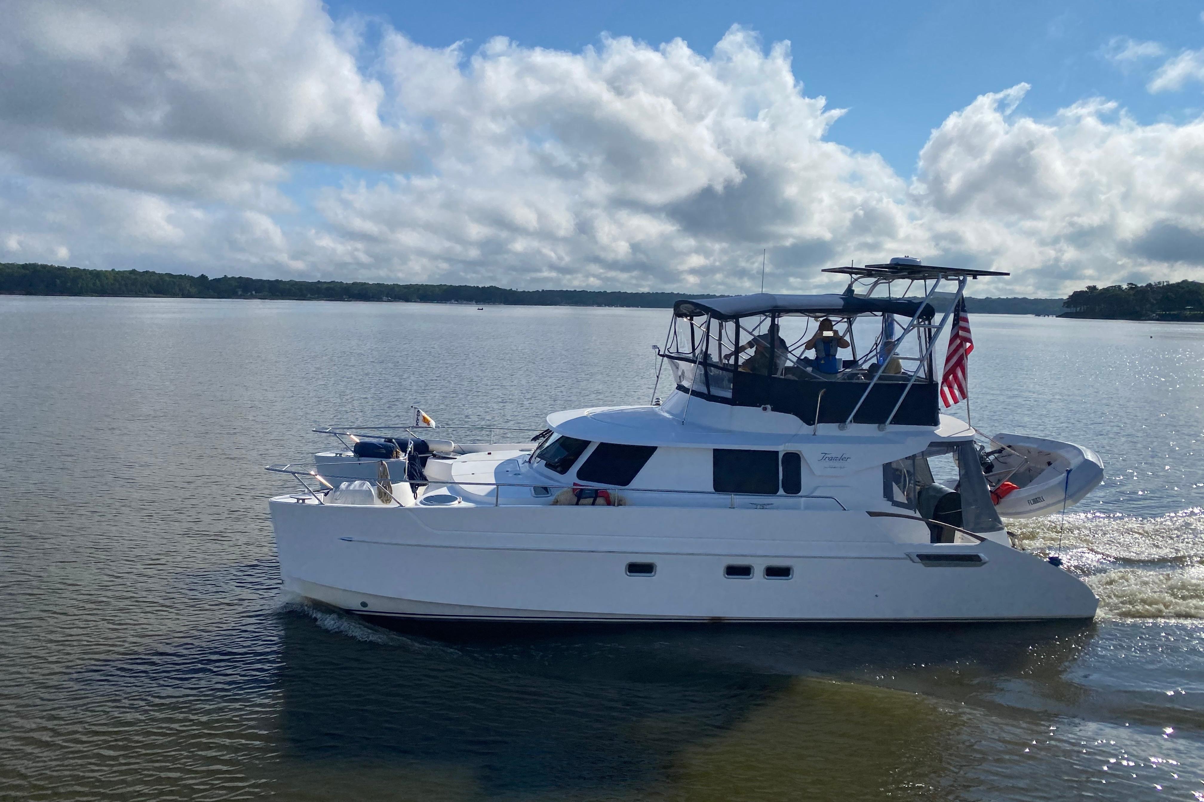 2005 Fountaine Pajot Maryland 37 cruising on a calm lake under a cloudy sky.