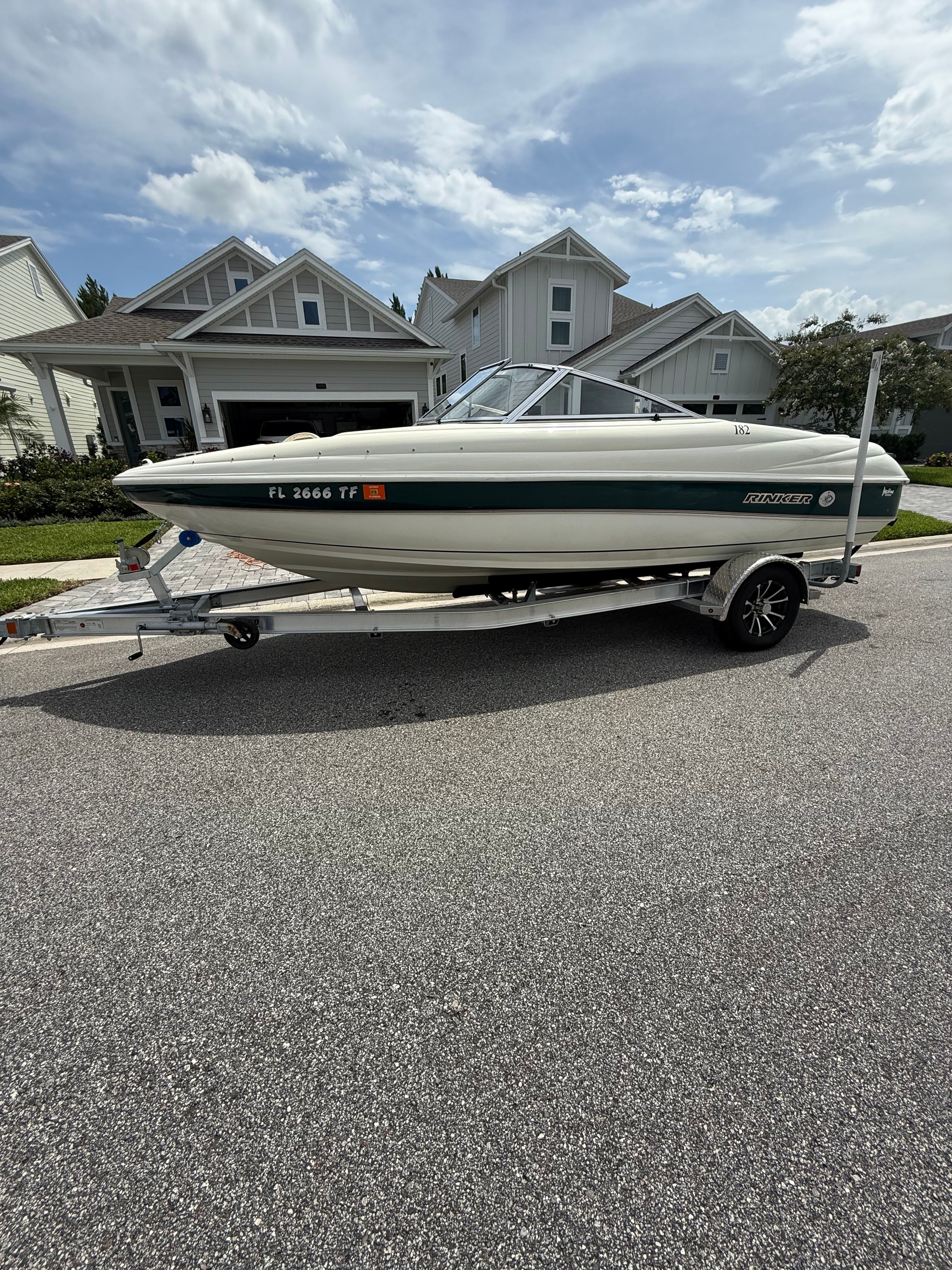 A 1998 Rinker Captiva boat on a trailer in a residential neighborhood.